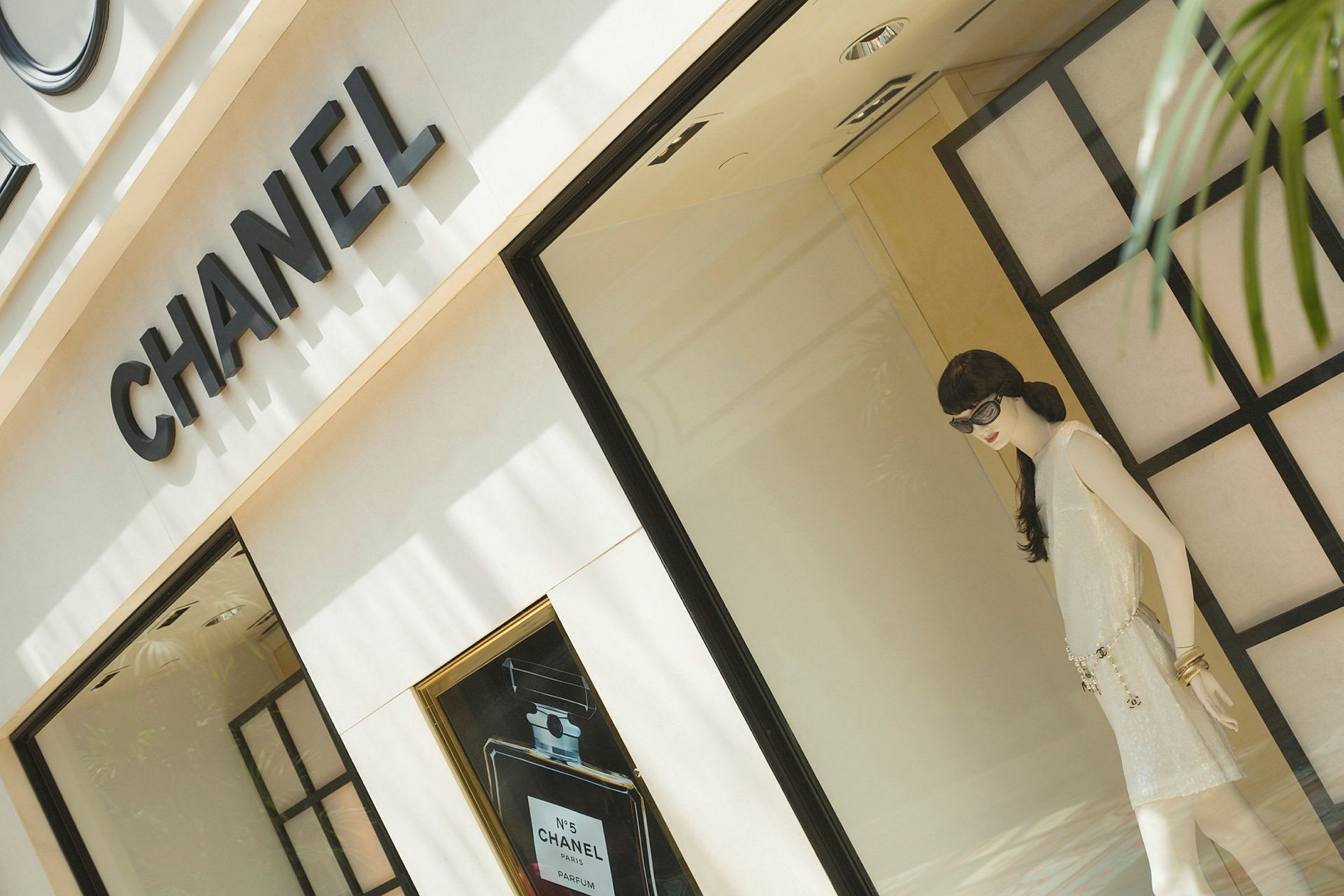 Skyltfönster tillhörande en Chanel-butik, innehållande en docka i en elegant klädsel. (AI-genererad text)