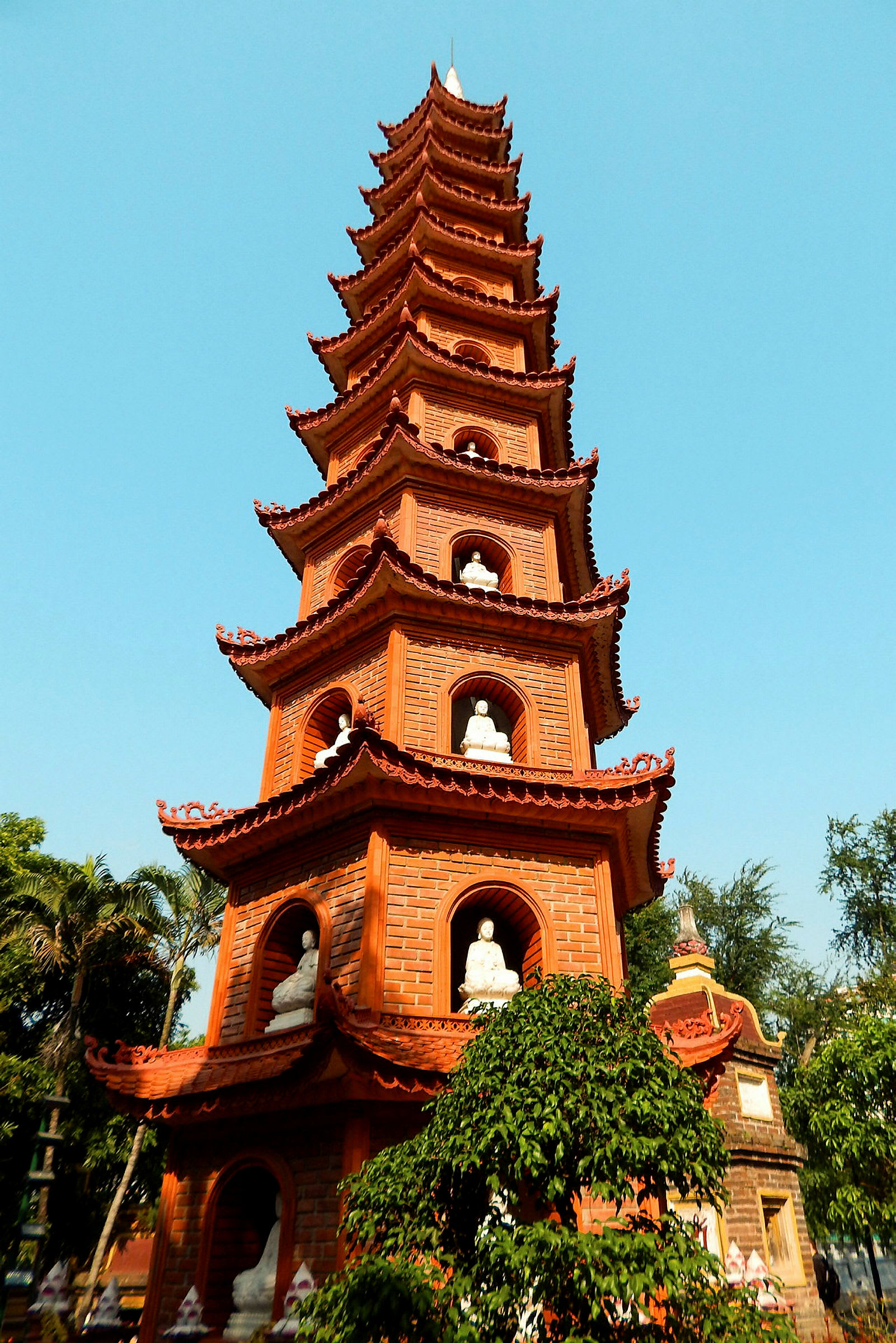 En pagodbyggnad i rött tegel med flera nivåer och statyer. (AI-genererad text)