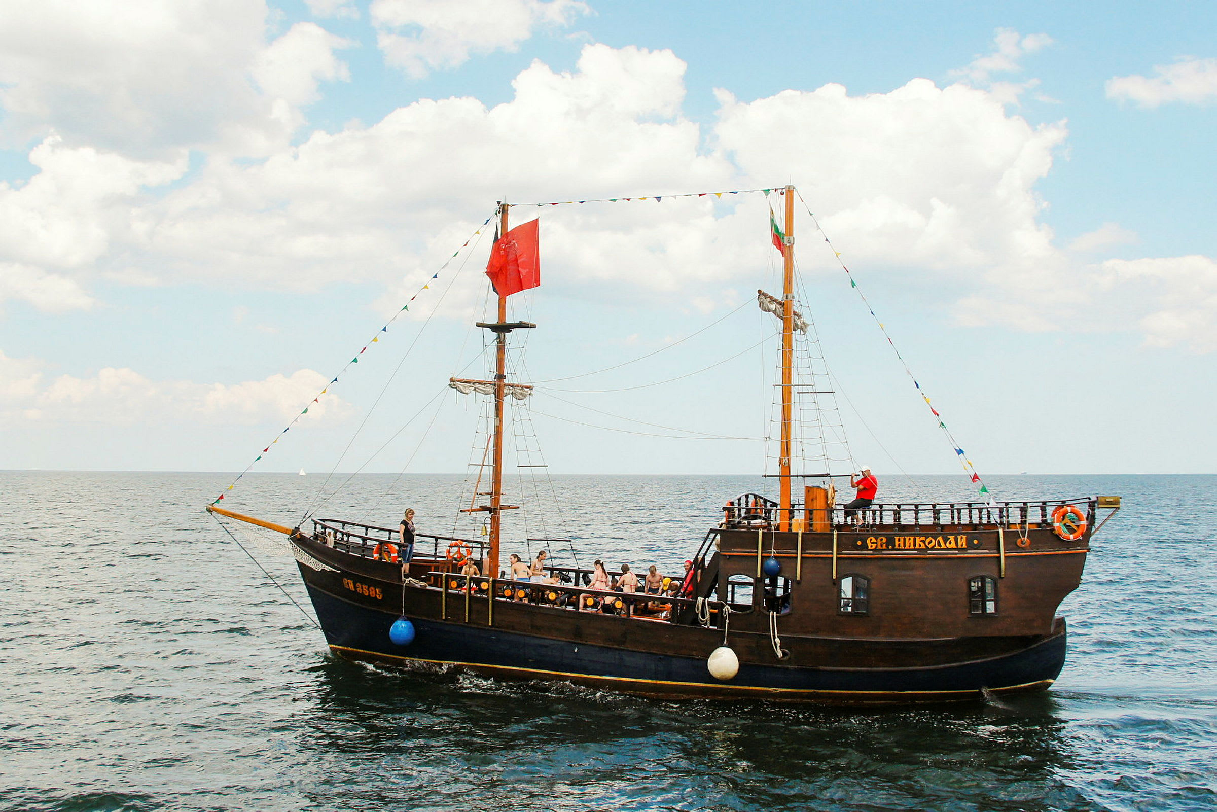 Ett traditionellt segelfartyg på det öppna havet med människor ombord. (AI-genererad text)