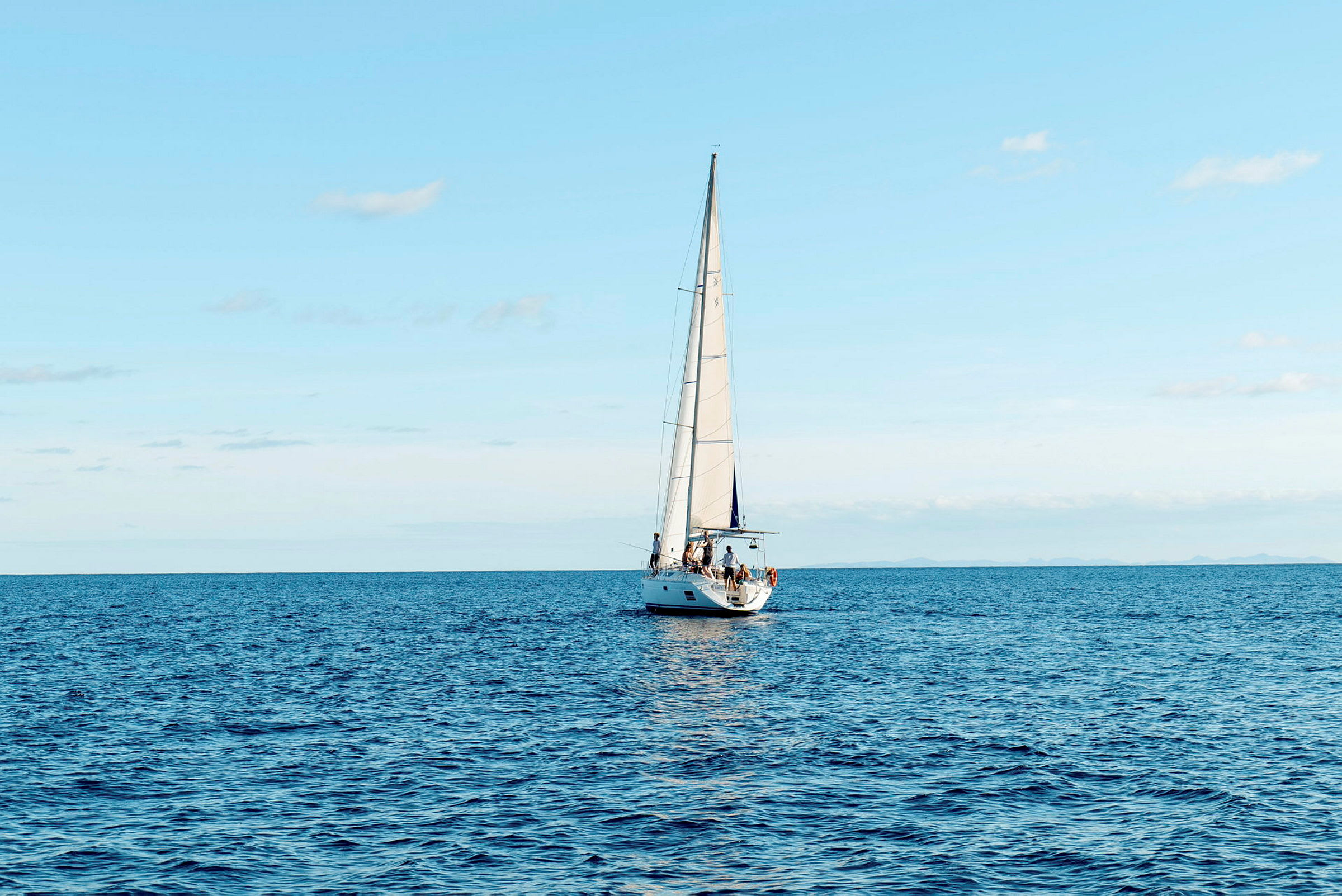 En segelbåt seglar på ett öppet hav under en klar himmel. (AI-genererad text)