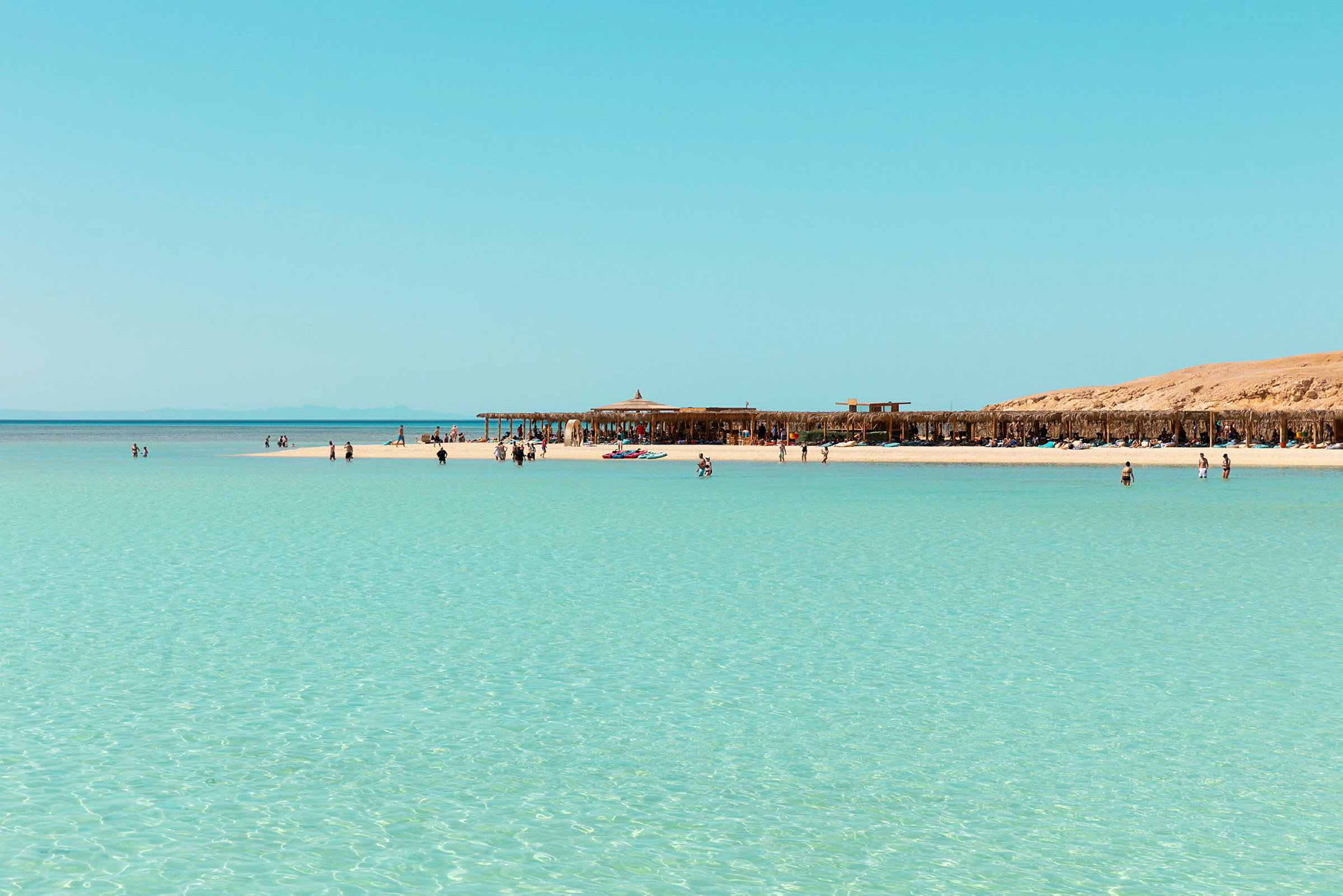Strand med turkost vatten och människor som badar. (AI-genererad text)