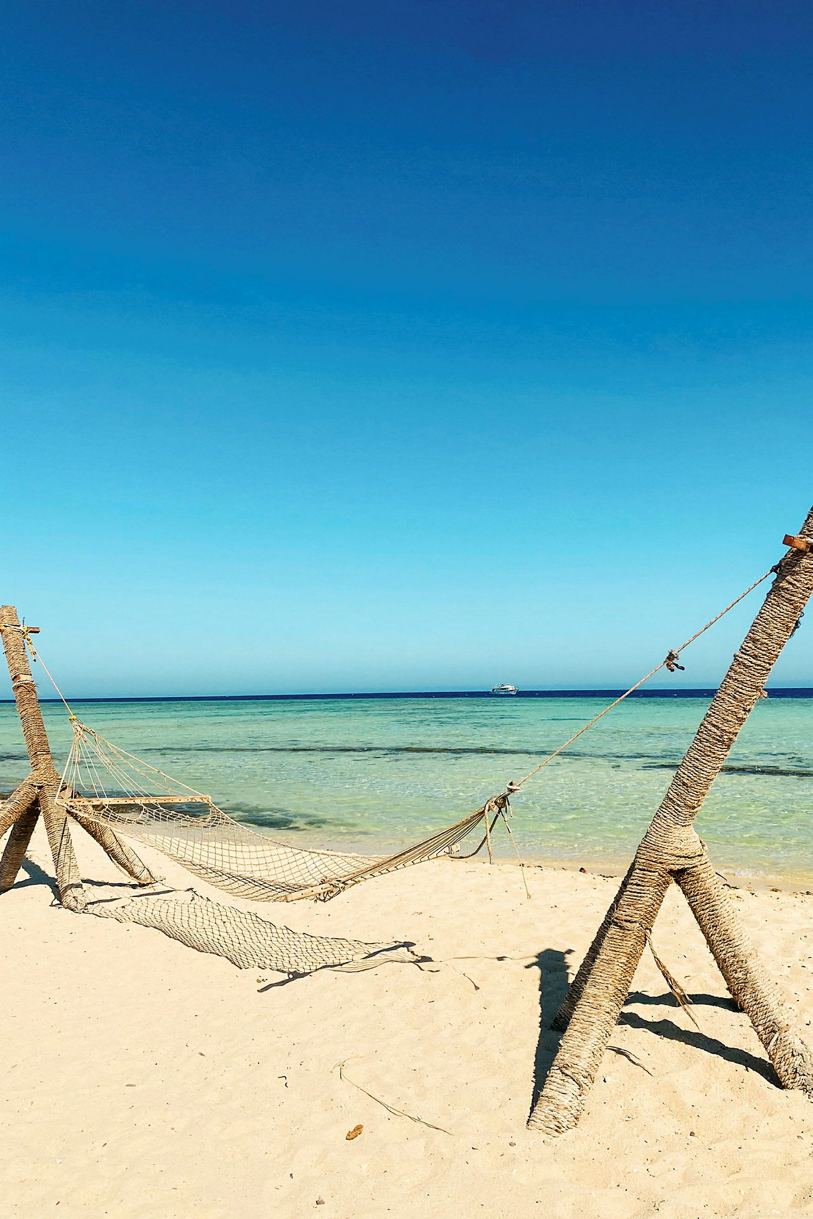En hängmatta på en sandstrand vid havet. (AI-genererad text)