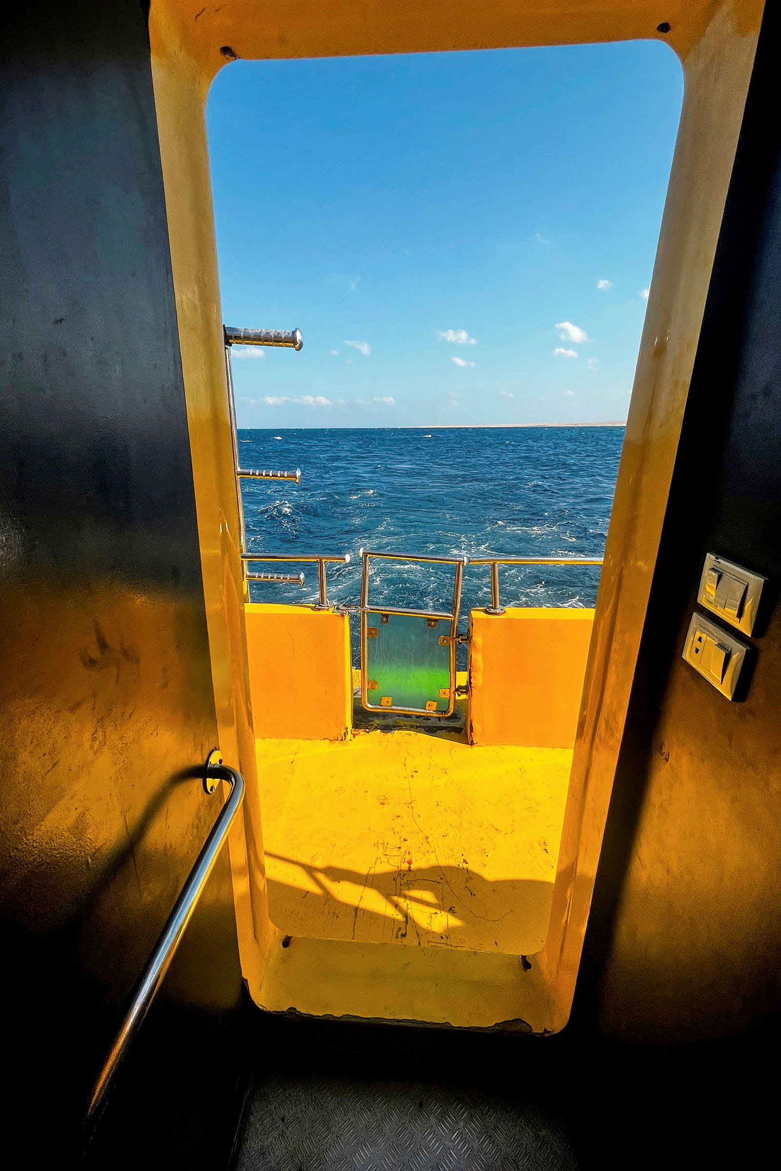 Utsikt över havet genom en gul dörröppning på ett fartyg. (AI-genererad text)