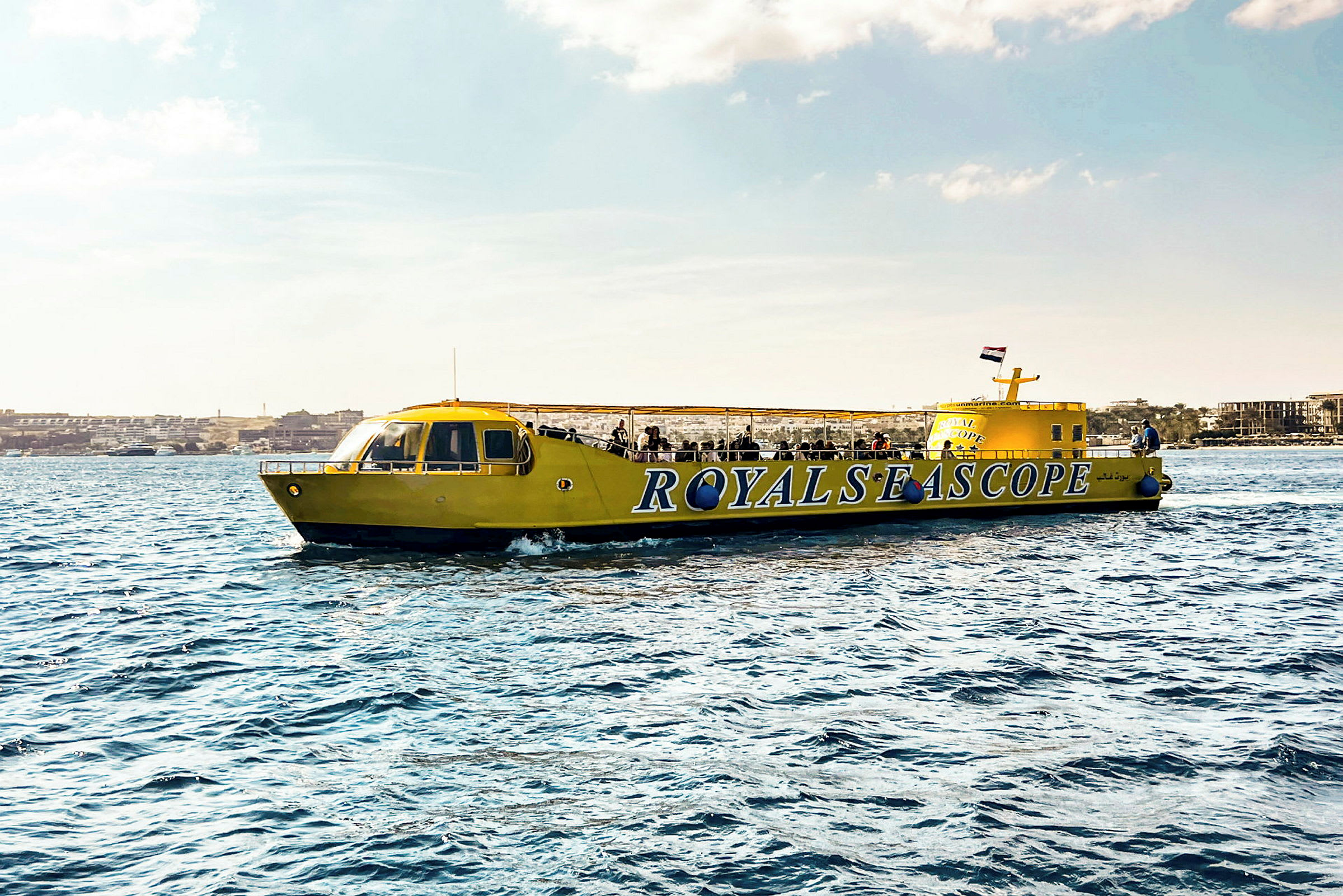 En gul sightseeingbåt med texten 'ROYALS SEA SCOPE' syns på vattnet. (AI-genererad text)