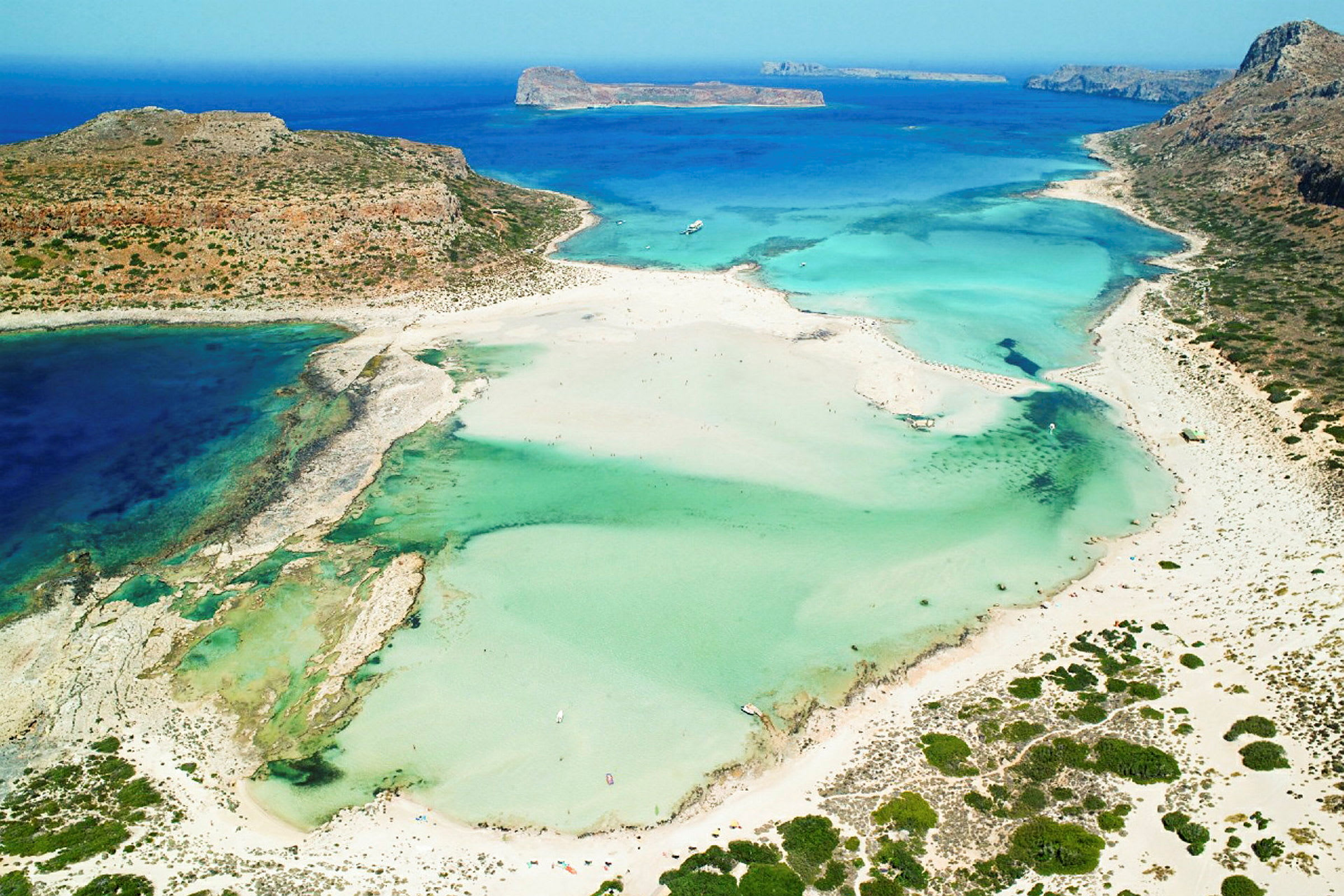 Flygbild av en strand med turkost vatten och omgivande sanddyner. (AI-genererad text)