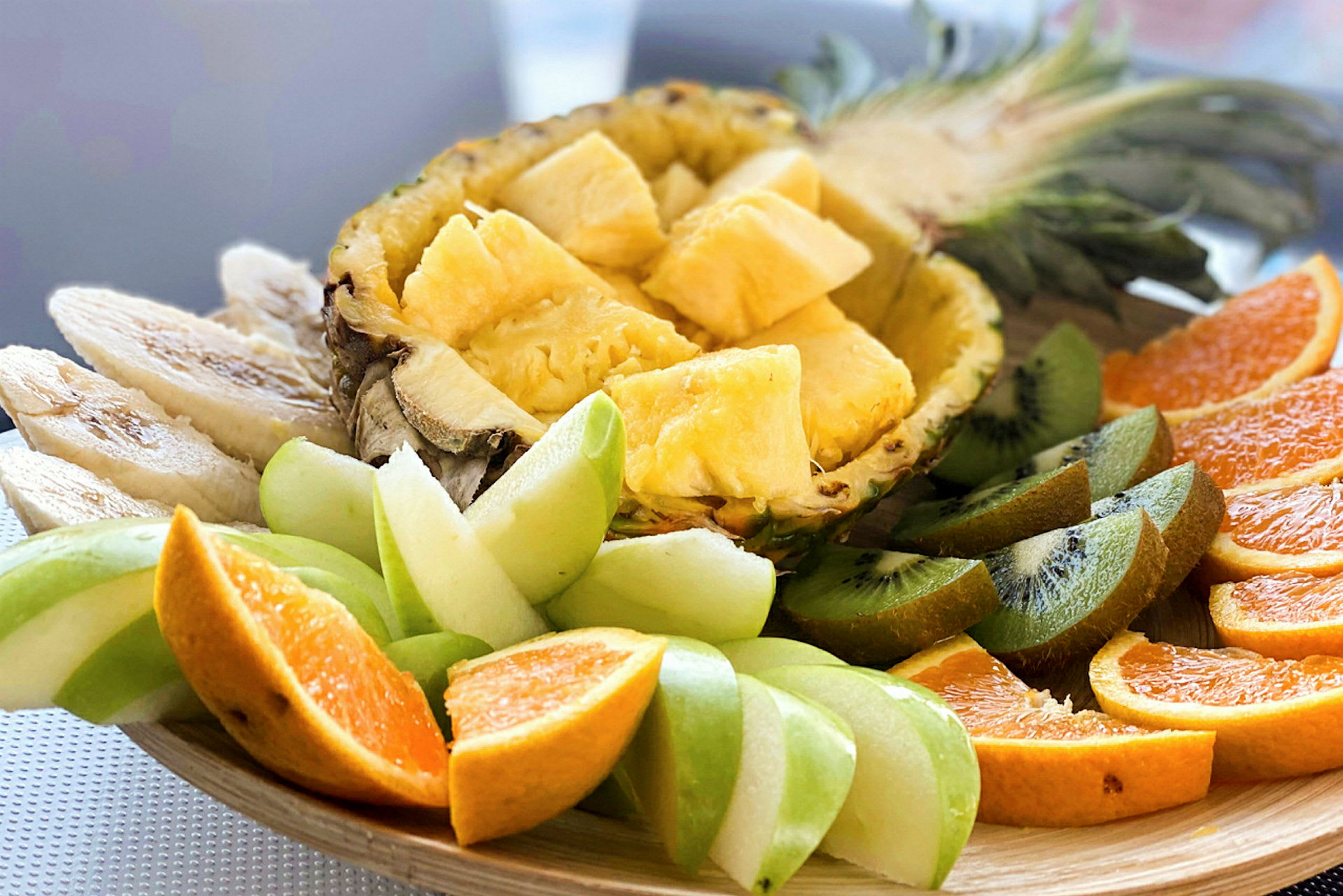 Ett fat med olika skivade frukter, inklusive ananas, kiwi, apelsin och gröna äpplen. (AI-genererad text)