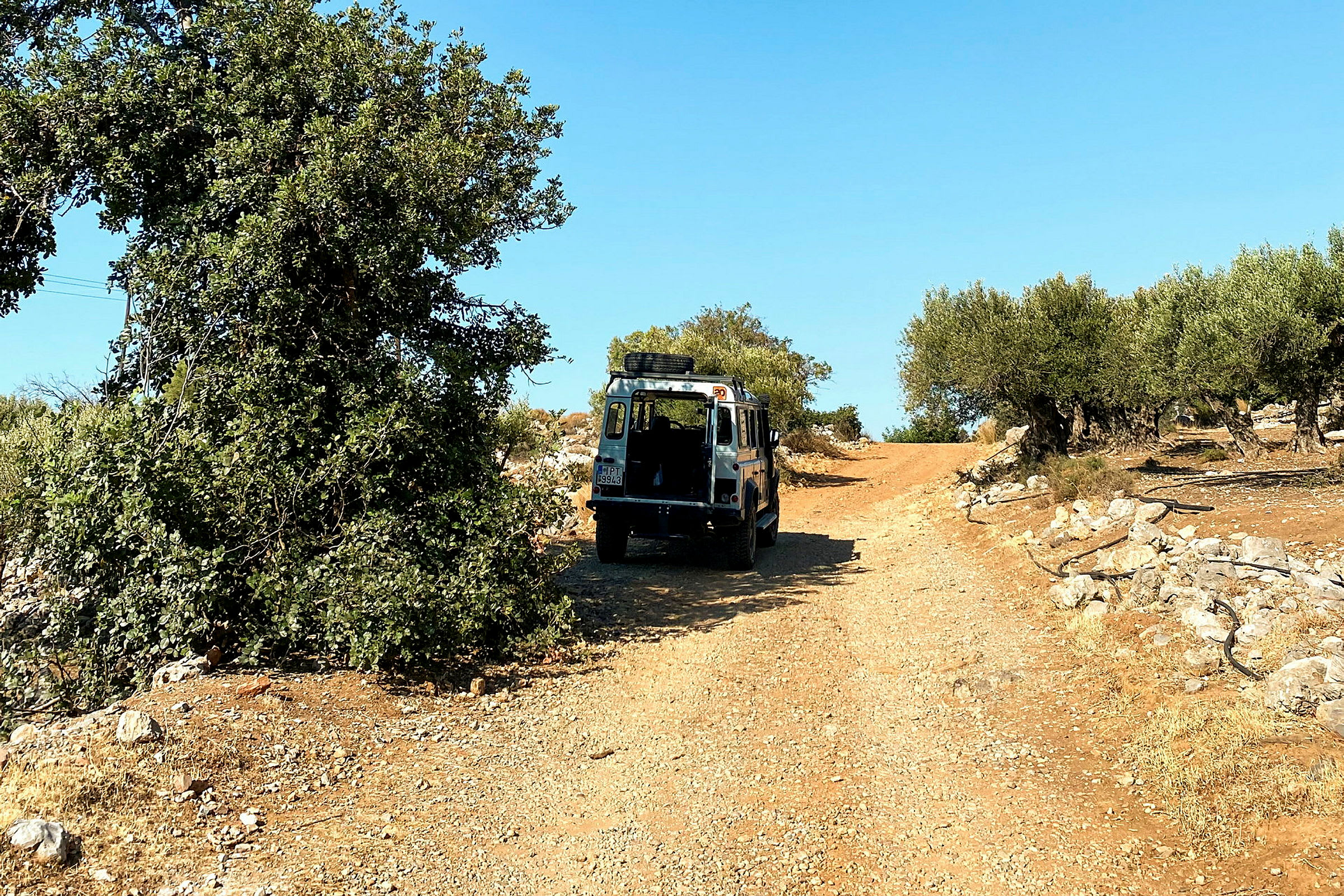 Ett terrängfordon parkerat på en grusväg omgiven av träd och vegetation. (AI-genererad text)