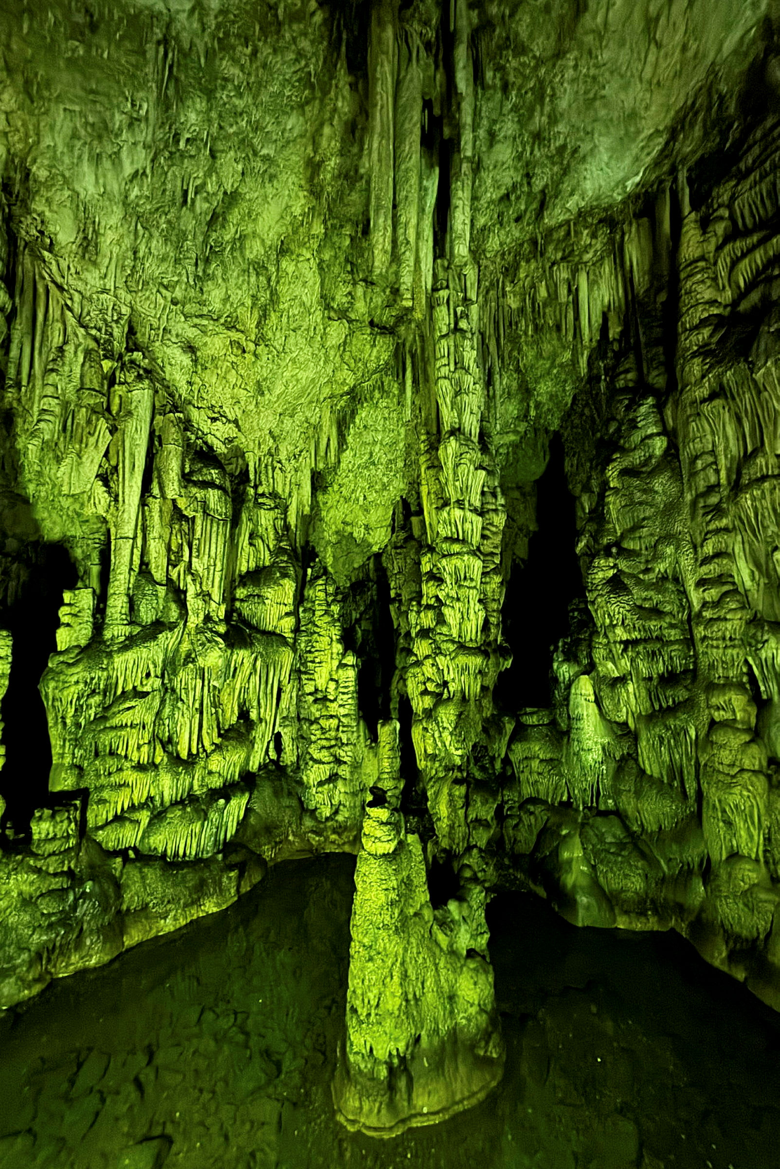 En upplyst grotta med stalaktiter och stalagmiter. (AI-genererad text)