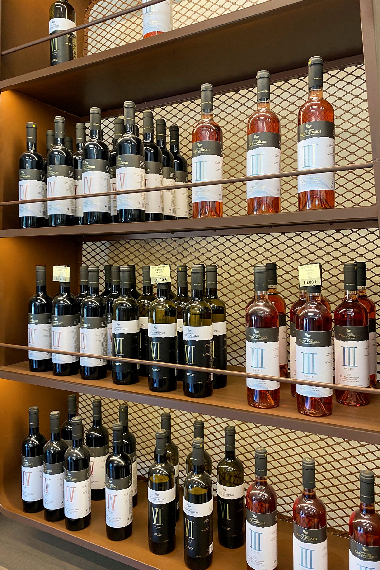 Hylla med flaskor av vin i olika sorter och etiketter, på en bronsfärgad bakgrund. (AI-genererad text)