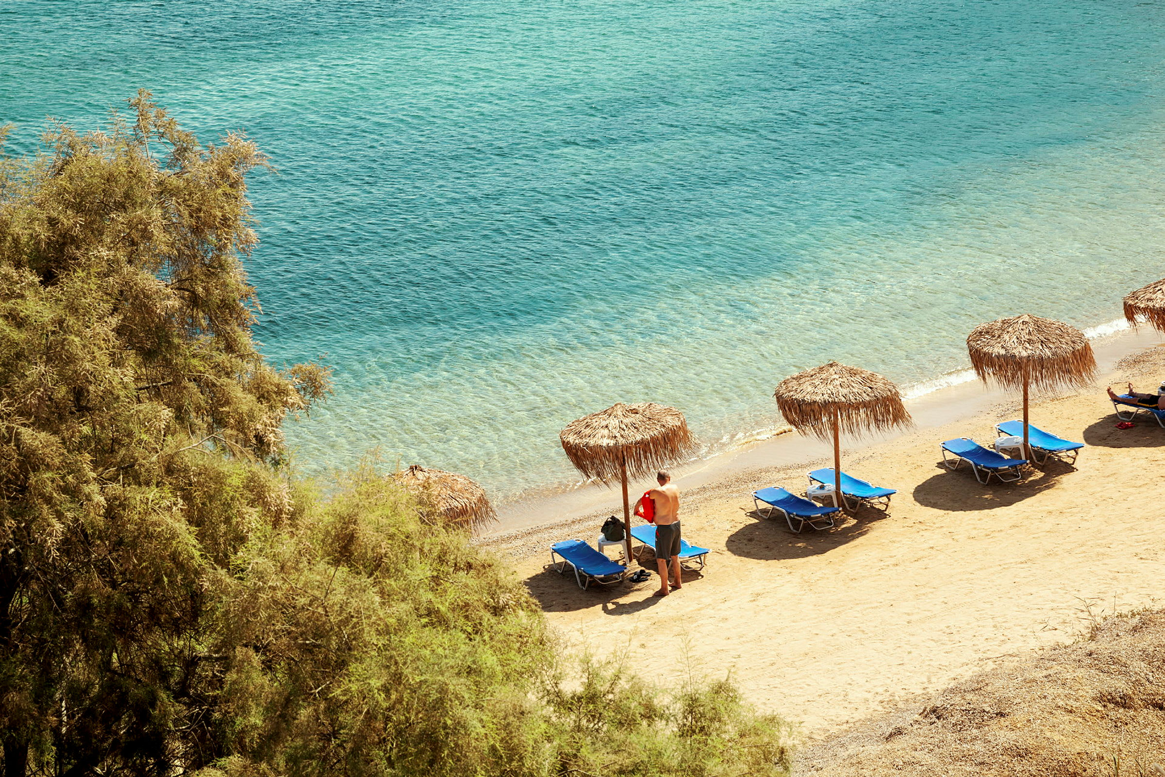 Strand med parasoller och solstolar vid havet. (AI-genererad text)