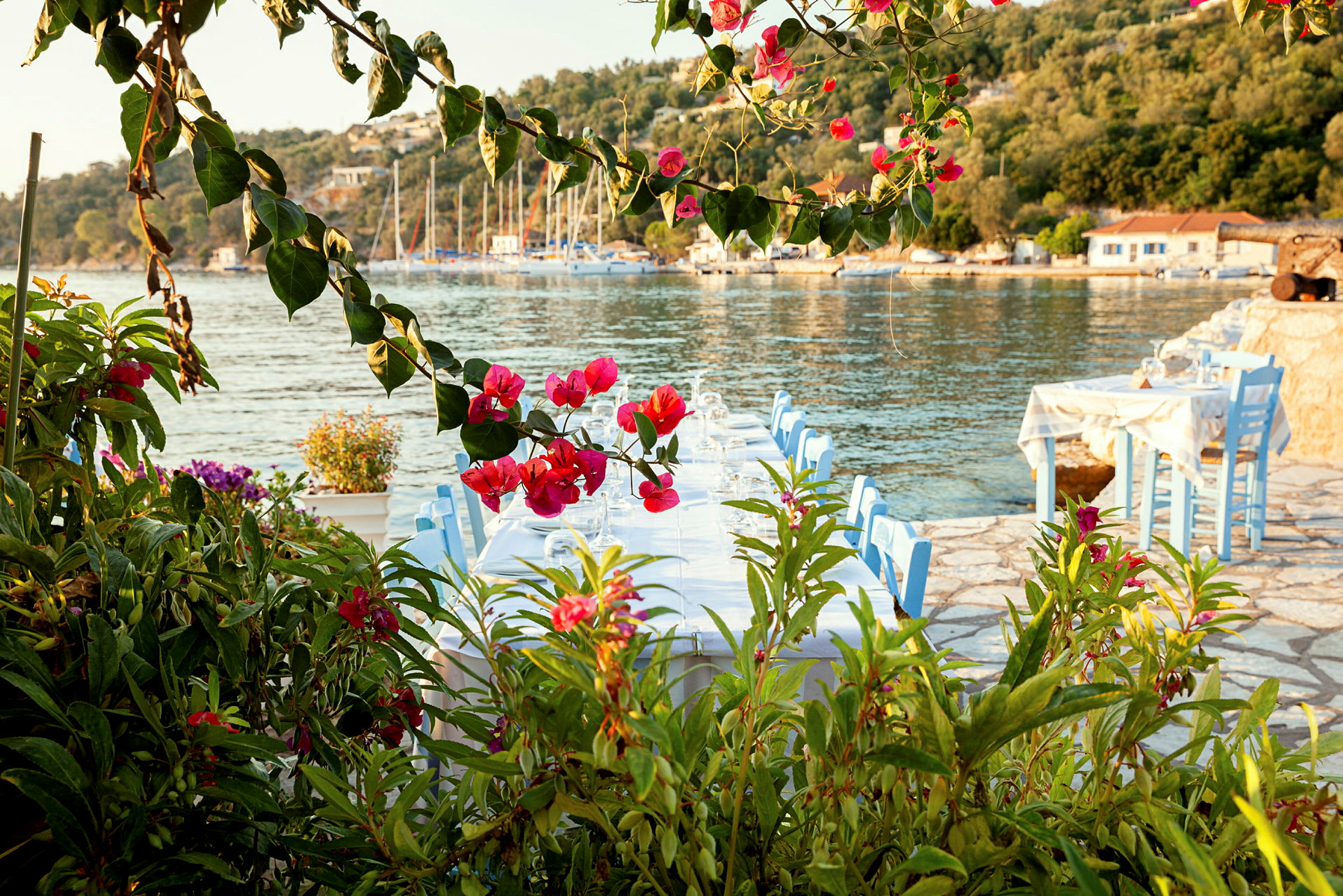 Strandnära restaurangbord med utsikt över havet och omgiven av blommor. (AI-genererad text)