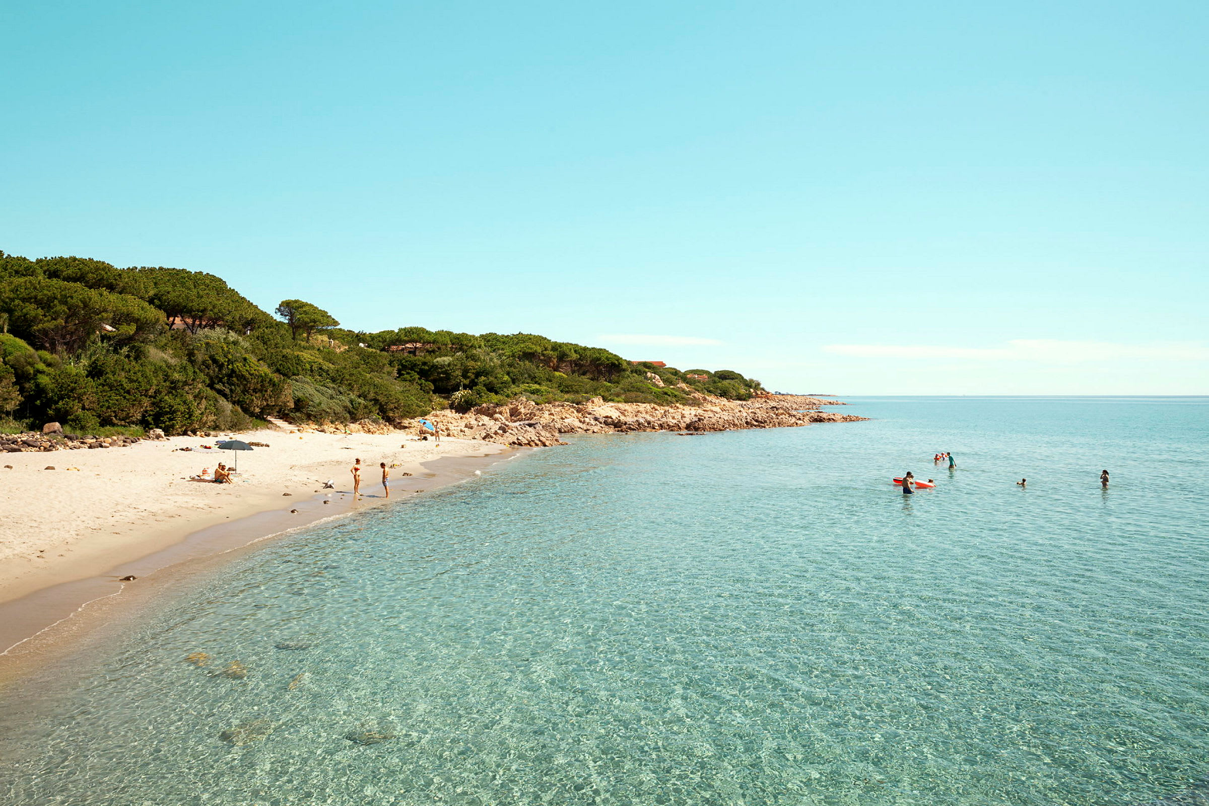 Sandstrand med klart vatten och människor som simmar. (AI-genererad text)