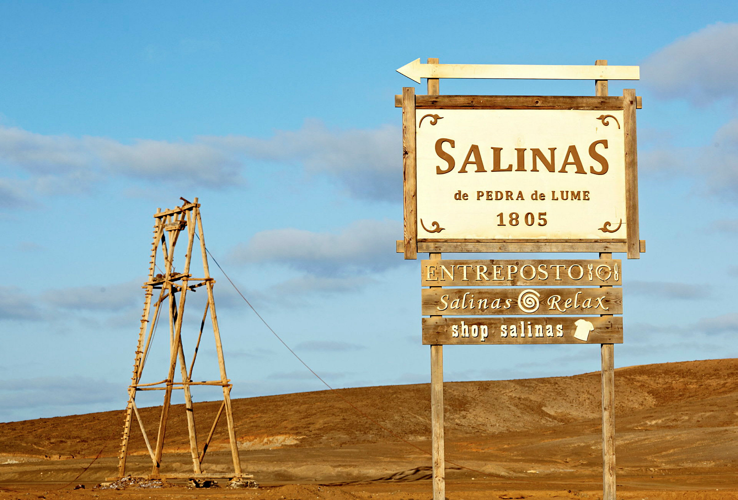Skylt som markerar Salinas de Pedra de Lume belägen i ett ökenområde. (AI-genererad text)