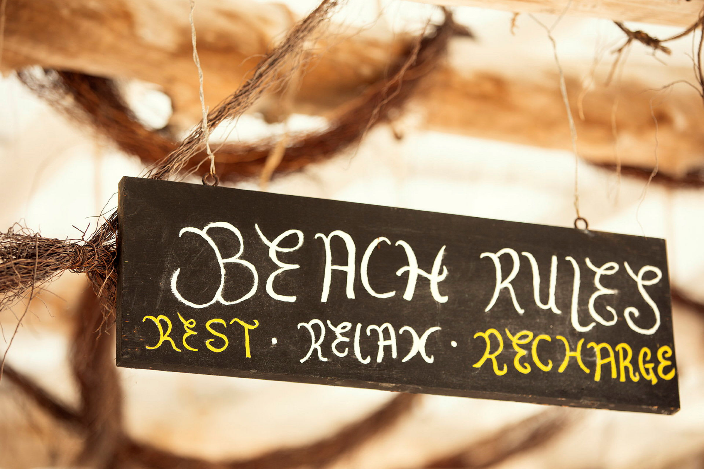 Svart skylt med texten 'Beach Rules: Rest, Relax, Recharge'. (AI-genererad text)