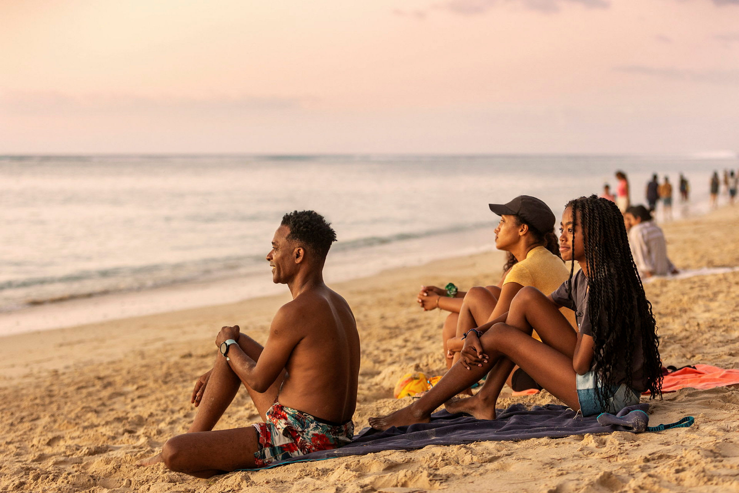 Personer sitter på en strand och blickar ut mot havet. (AI-genererad text)