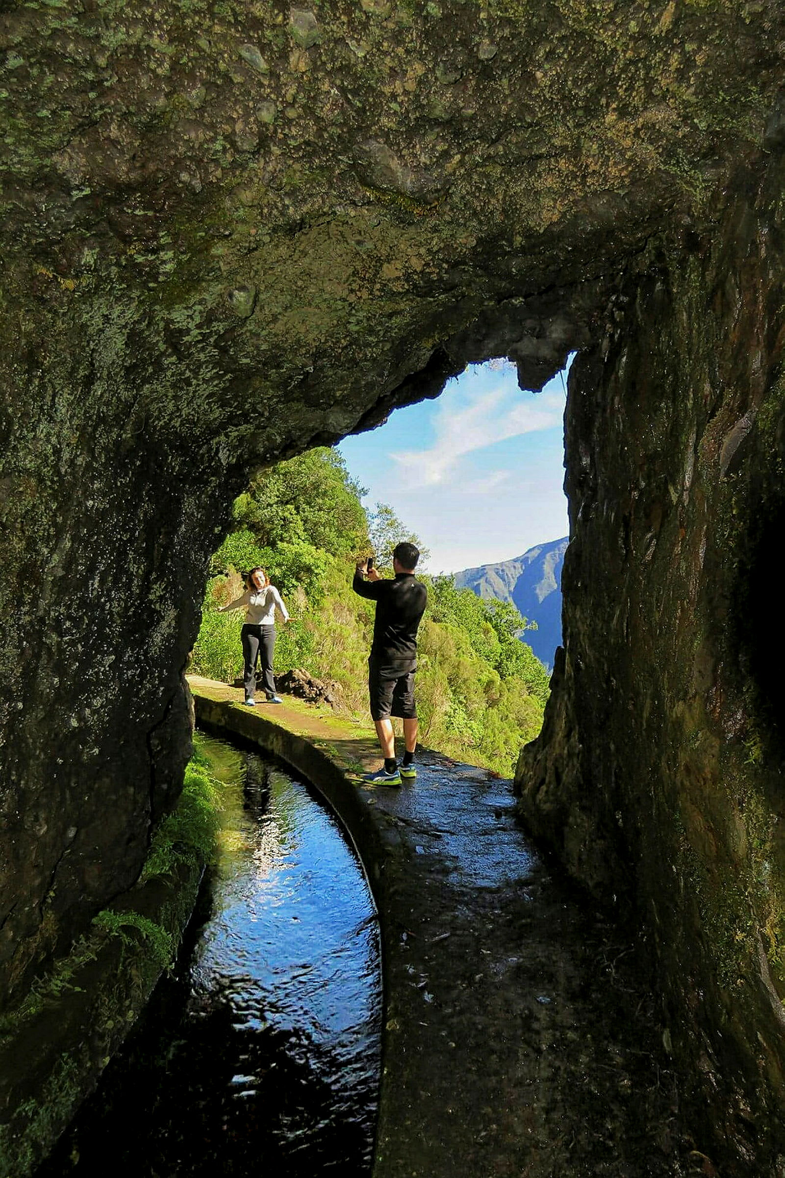 Person står vid bergstunnel och fotograferar landskap. (AI-genererad text)