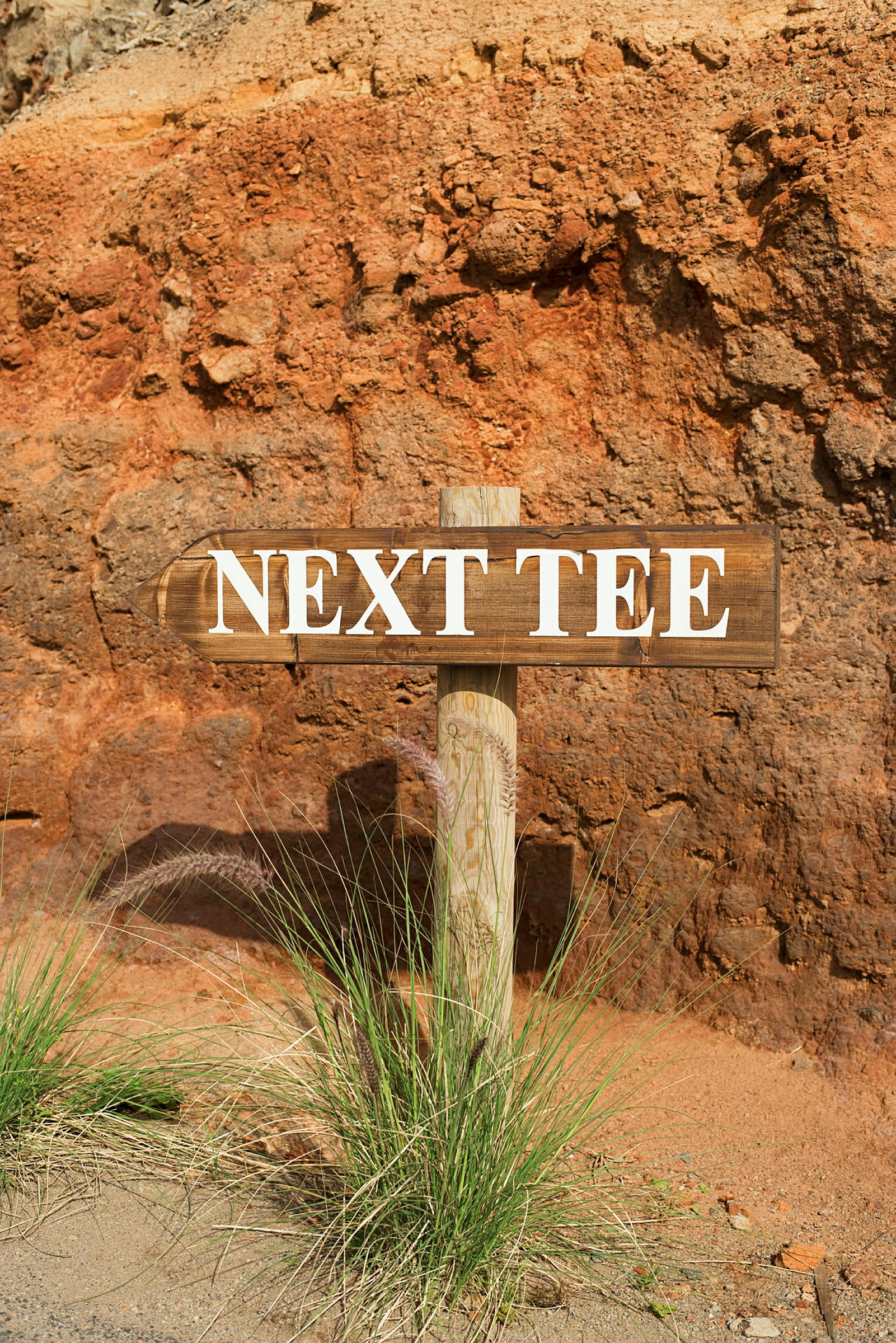 Skylt med texten 'Next Tee' vid en sluttning. (AI-genererad text)