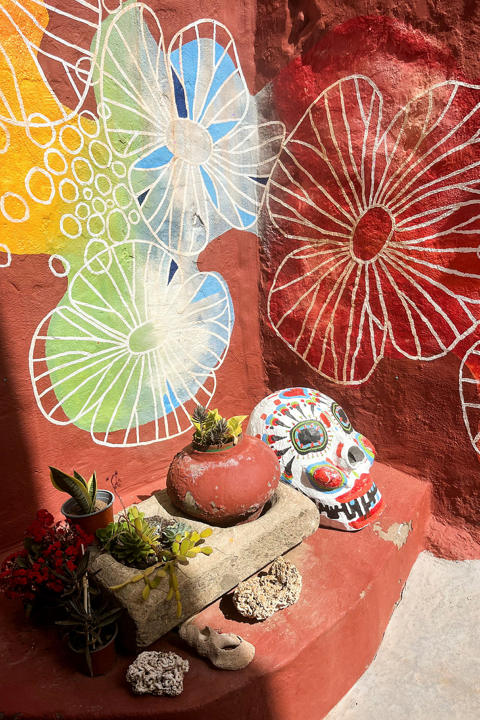 Muralmålning med blommor, en dekorativ målning av en döskalle och prydnadsföremål på en trappa. (AI-genererad text)