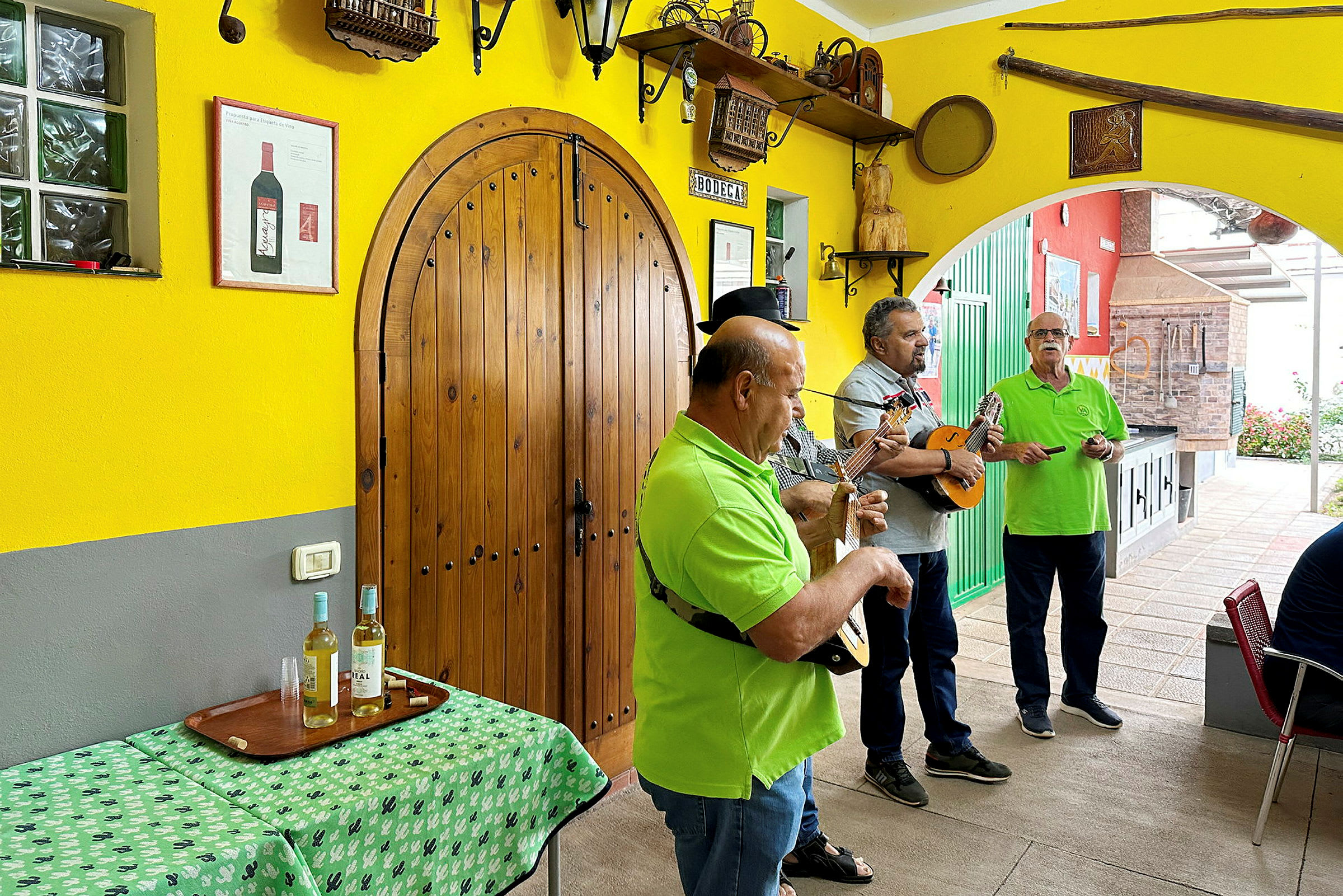 Personer spelar mandolin och gitarr på en terrass med gula väggar. (AI-genererad text)