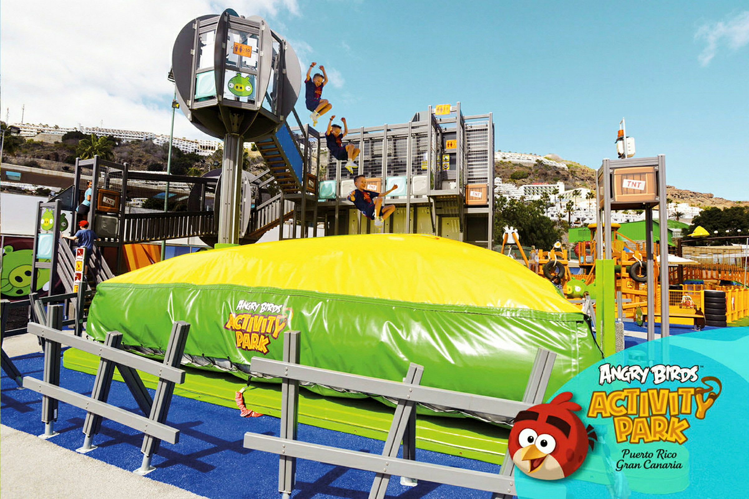 Ett aktivitetsområde utomhus vid Angry Birds Activity Park med en stor uppblåsbar kudde och flera lekstrukturer. (AI-genererad text)