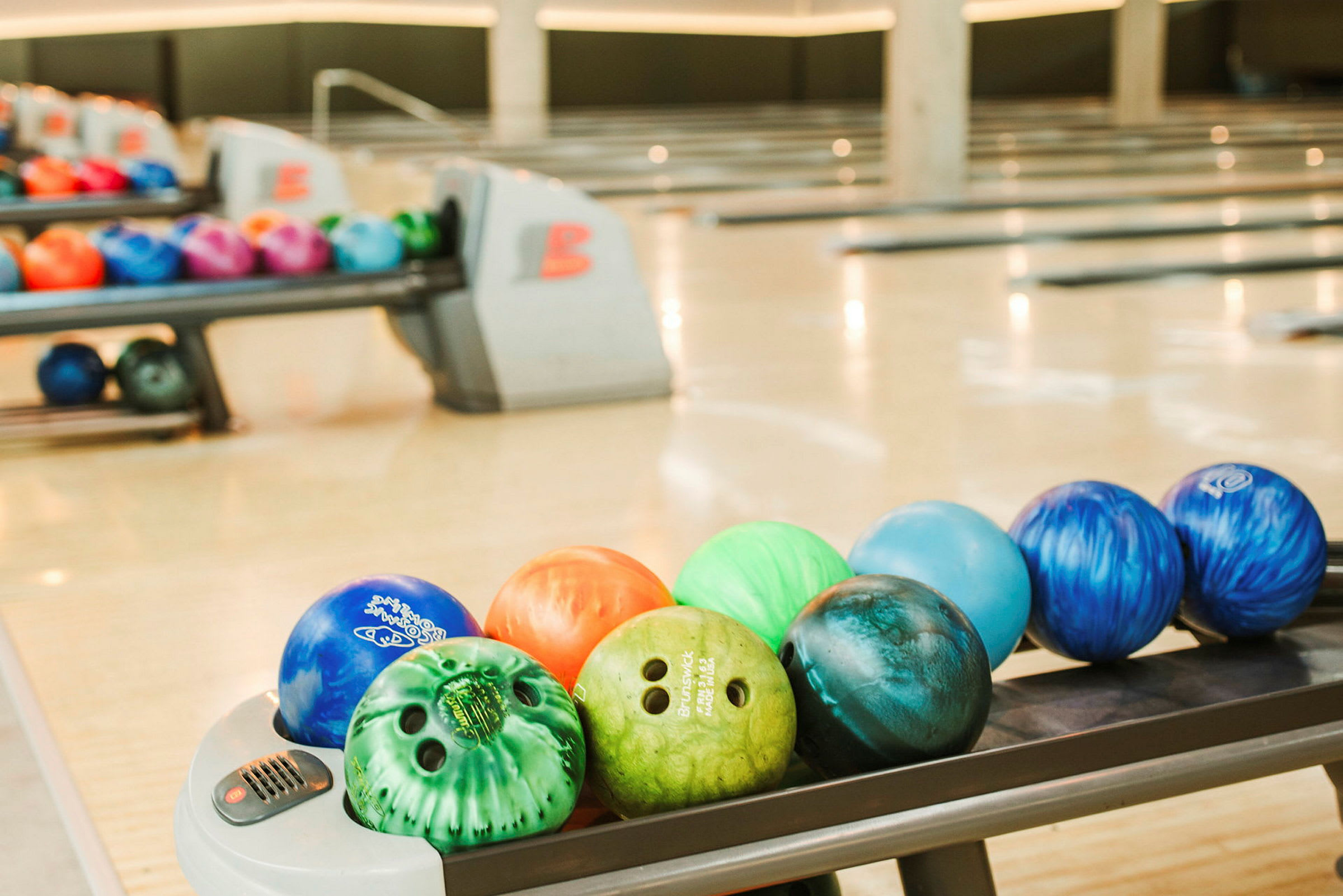 Bowlingbollar i olika färger på banorna i en bowlinghall. (AI-genererad text)
