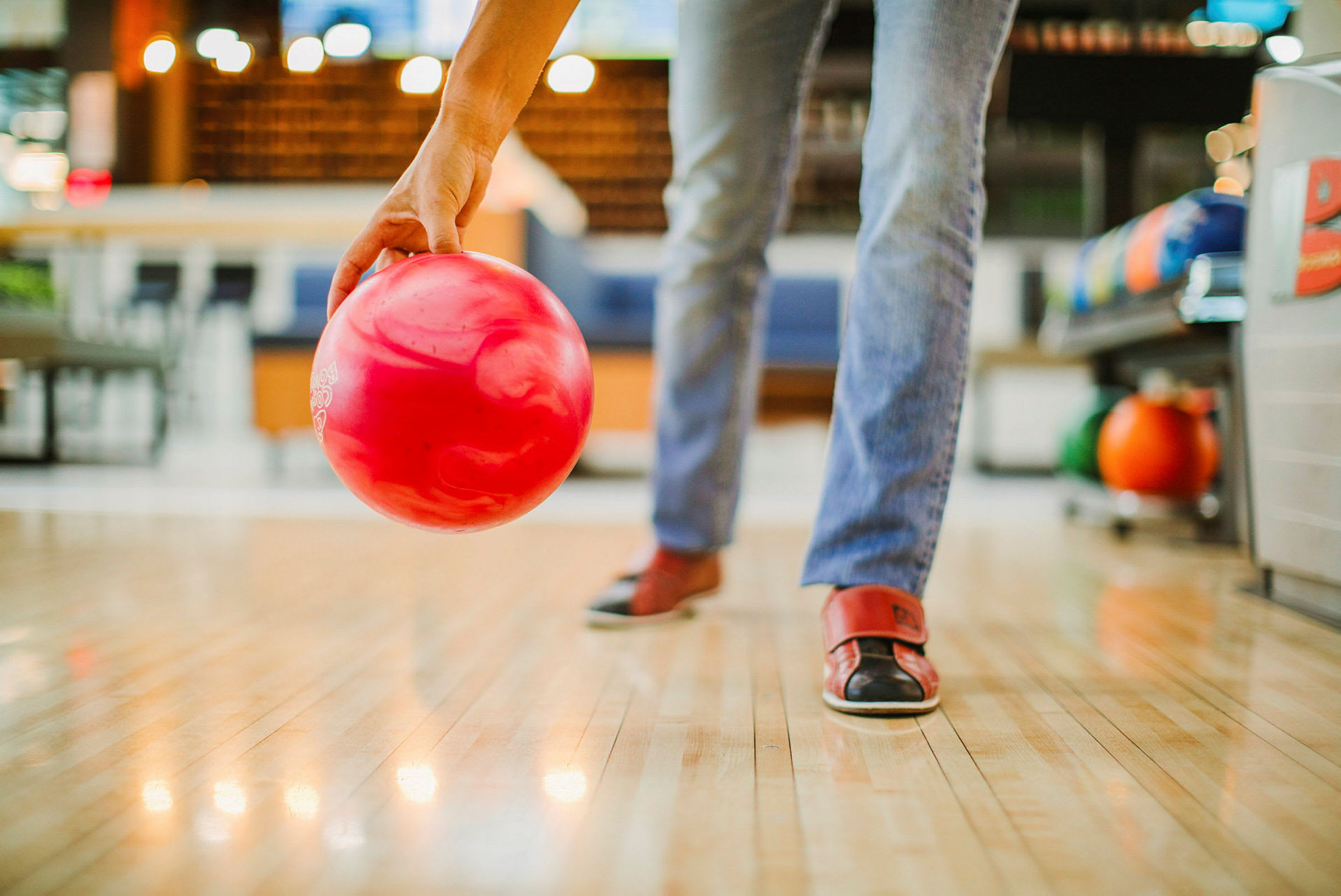 En person förbereder sig för att kasta en röd bowlingklot på en bana. (AI-genererad text)