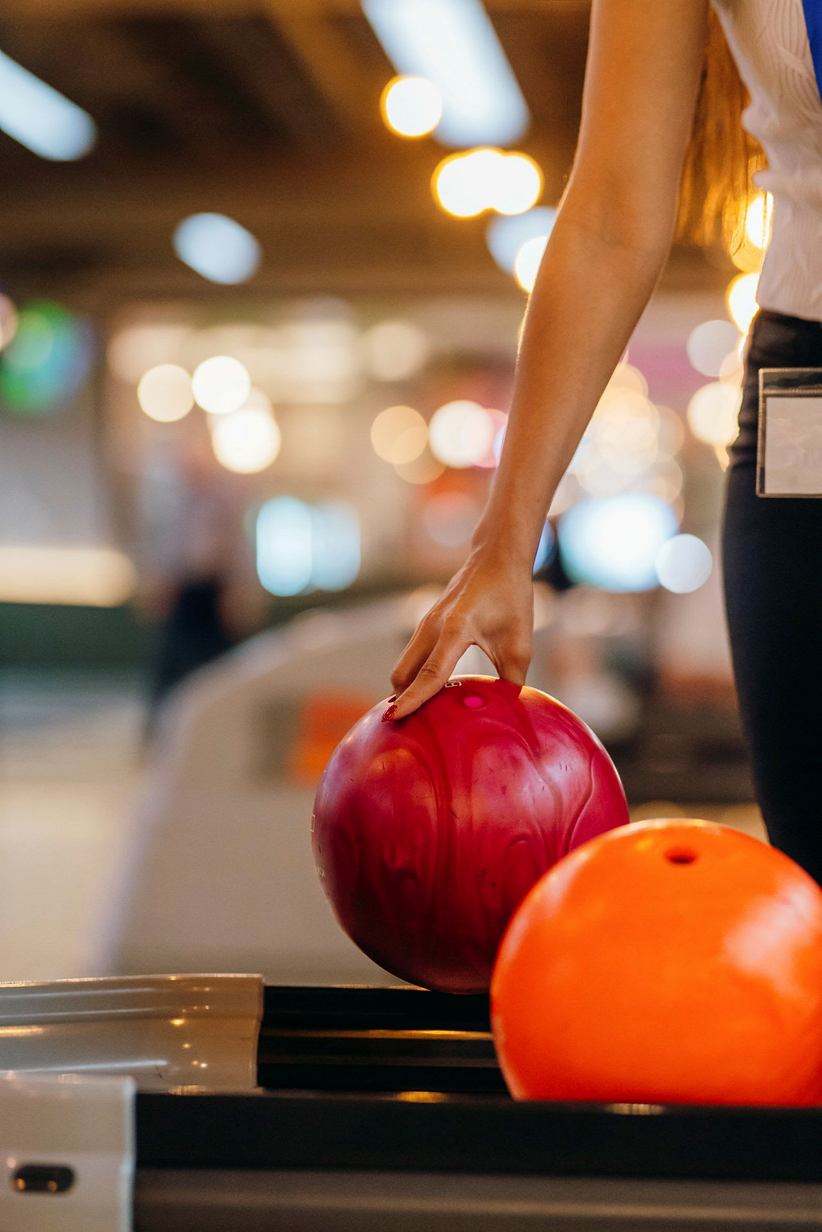 En person håller en rosa bowlingklot med handen. (AI-genererad text)