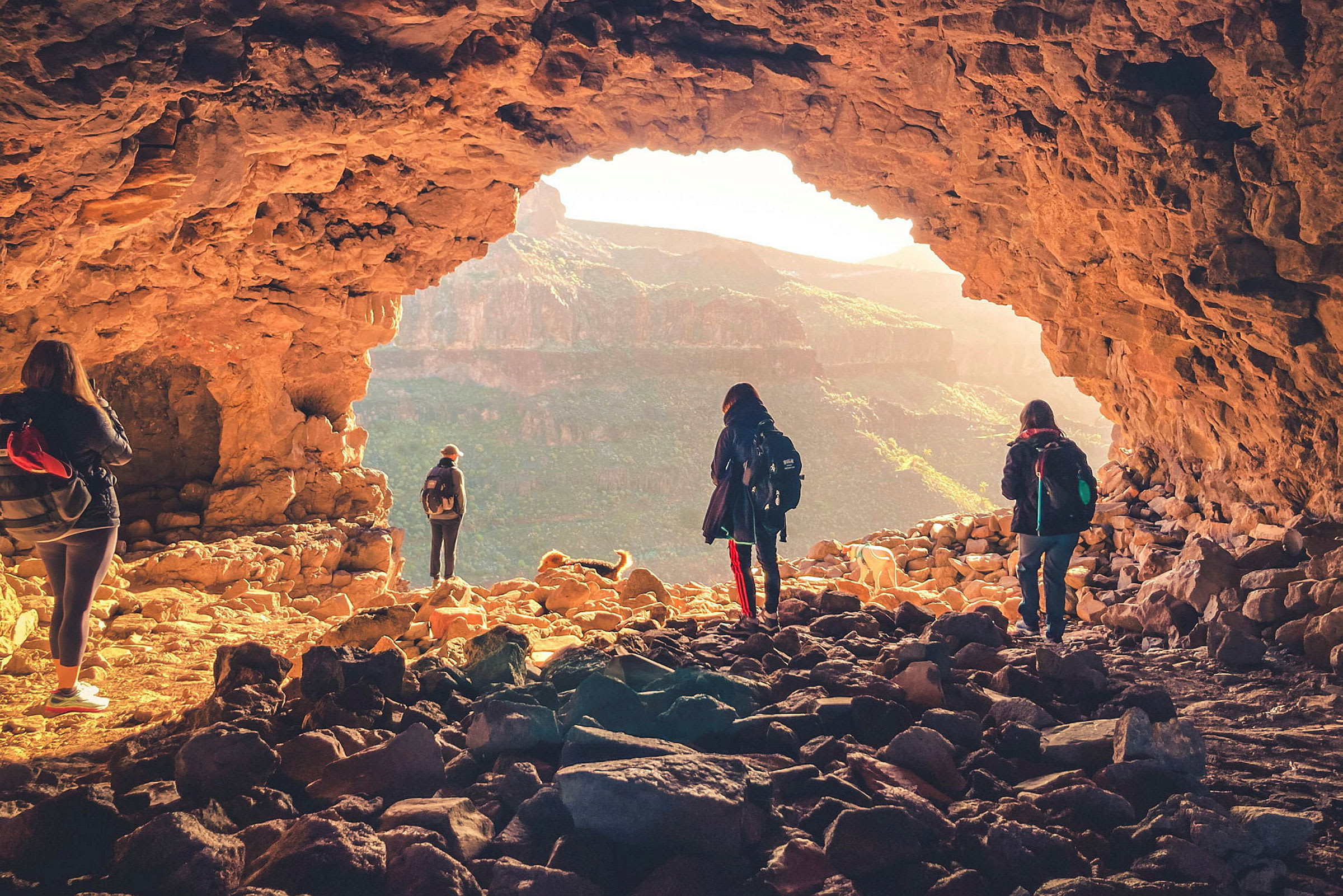 En grupp människor utforskar en grotta med utsikt över ett bergigt landskap. (AI-genererad text)