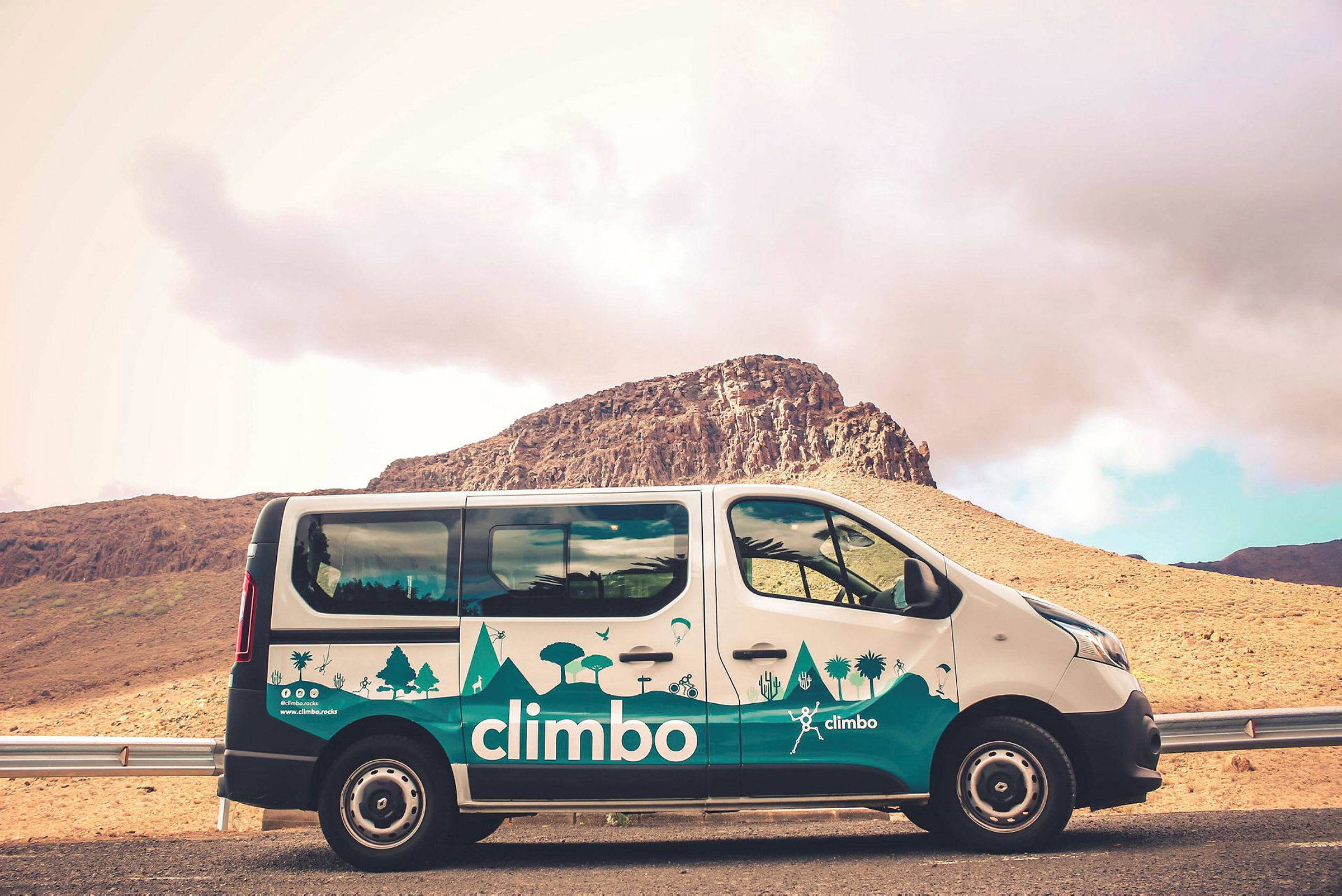 En bil med texten 'climbo' parkerad framför en bergig bakgrund. (AI-genererad text)