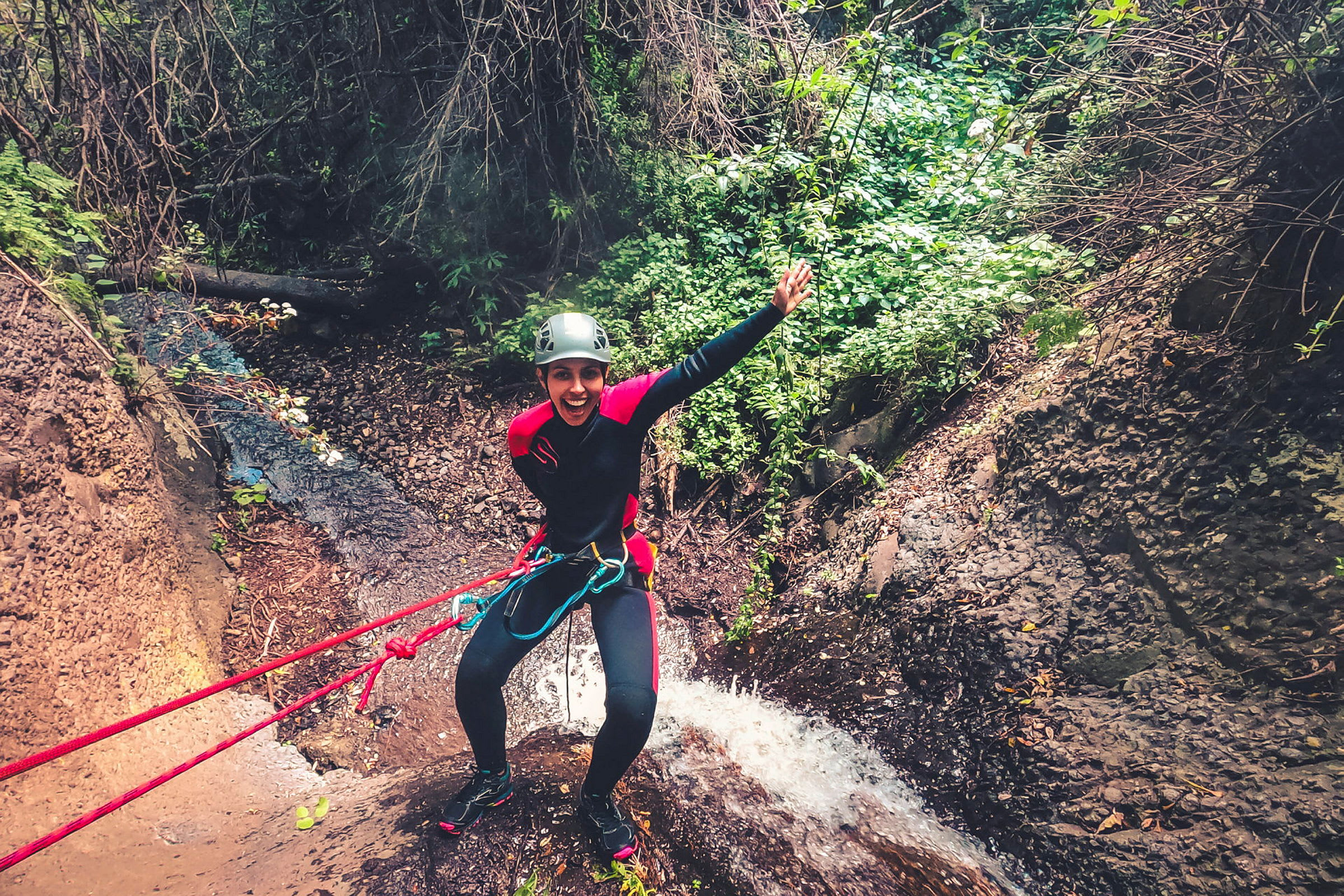 Person som utför rappelling vid ett vattenfall och omgiven av skog. (AI-genererad text)