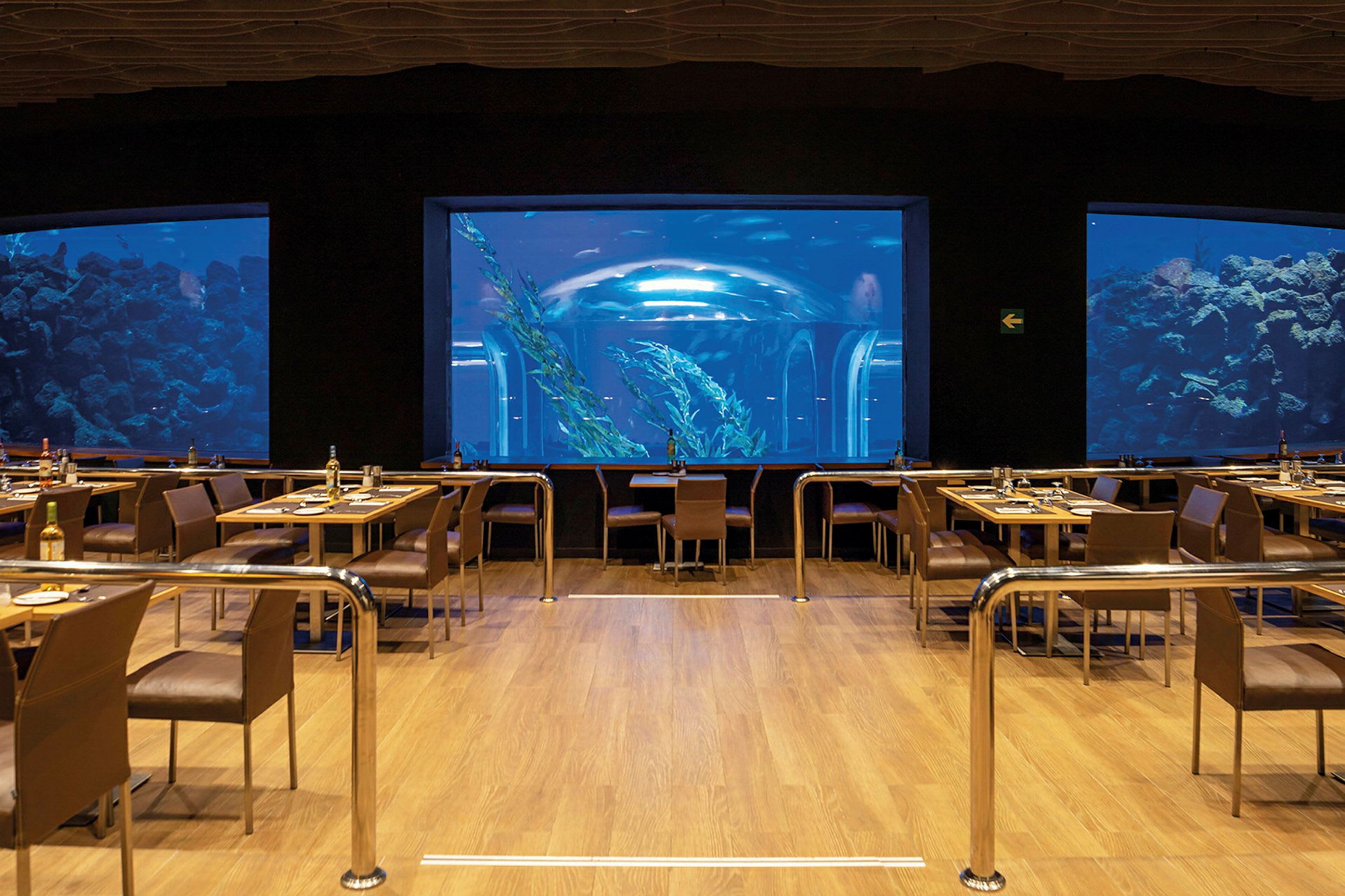 En restaurang med utsikt över ett stort akvarium med fiskar och undervattensmiljö. (AI-genererad text)