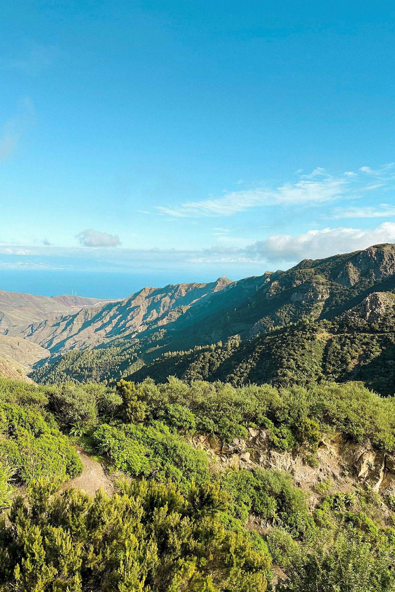Bergslandskap med grön vegetation och blå himmel. (AI-genererad text)
