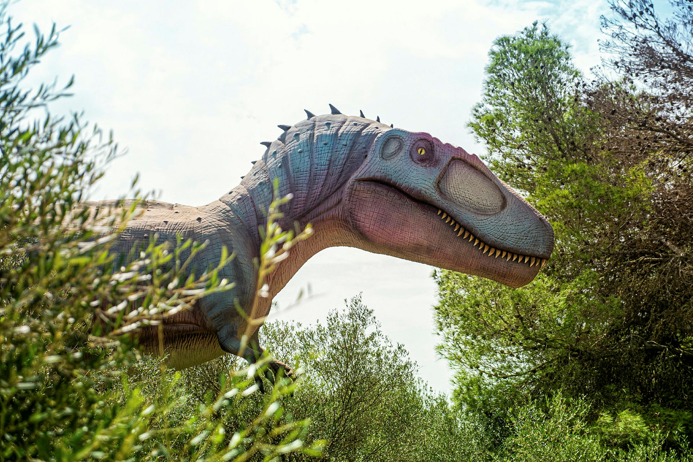 En replik av en dinosaurie ses delvis bland växtlighet och träd. (AI-genererad text)