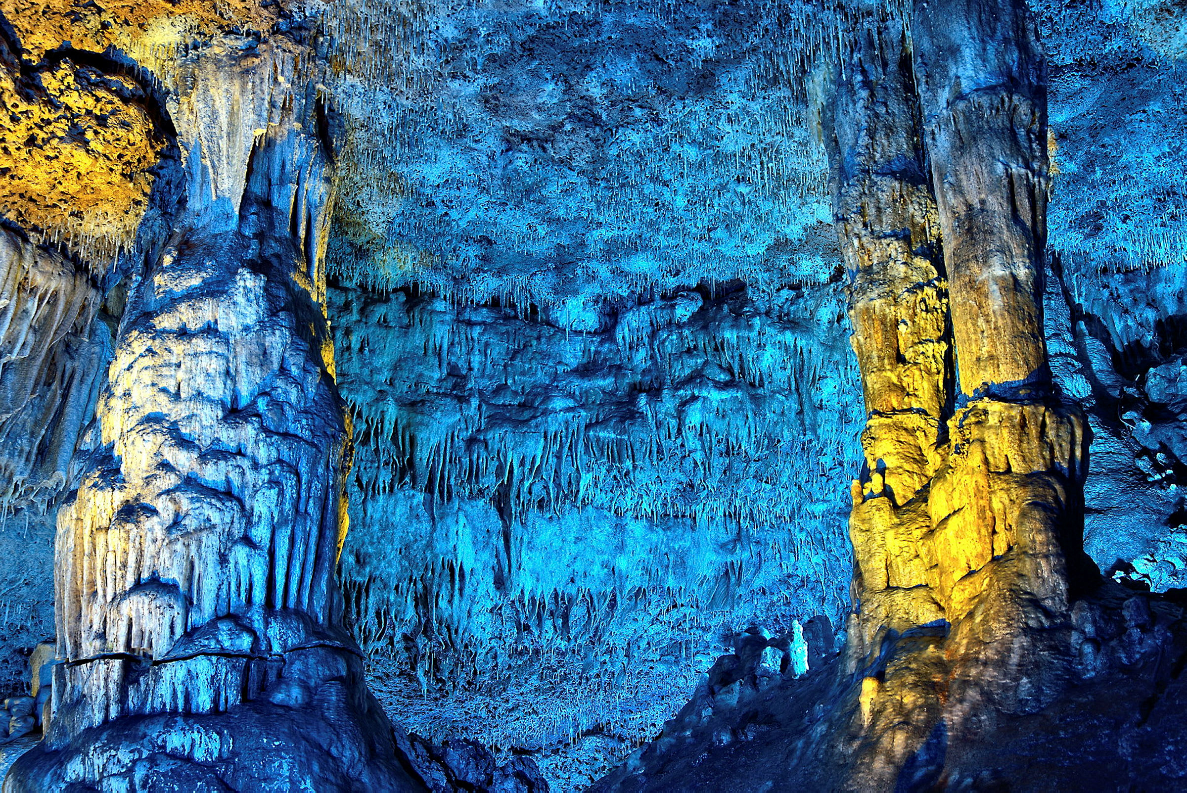 Ett grottsystem med färgglad belysning som lyser upp stalaktiter och stalagmiter. (AI-genererad text)