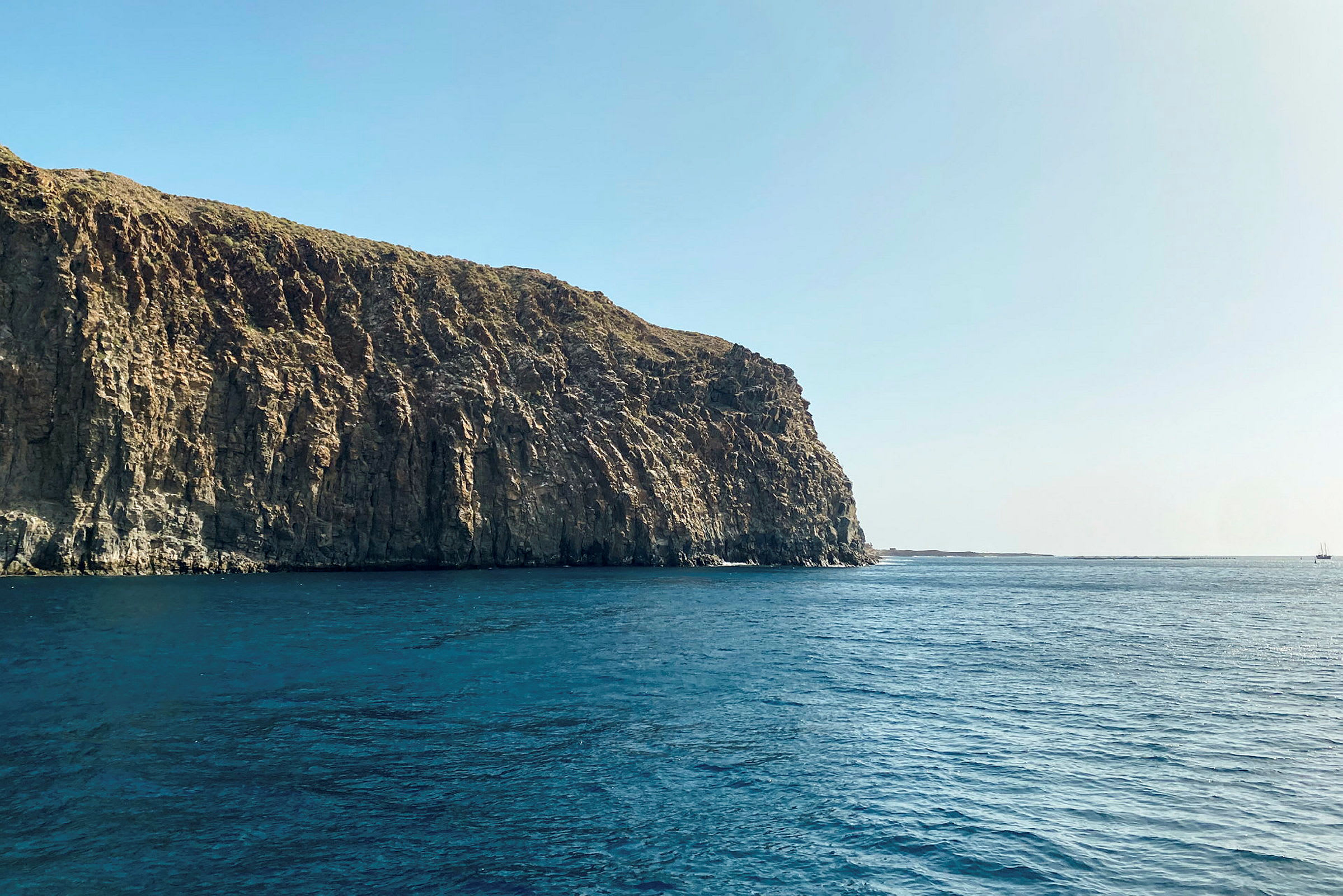 En hög klippa vid havet under klarblå himmel. (AI-genererad text)