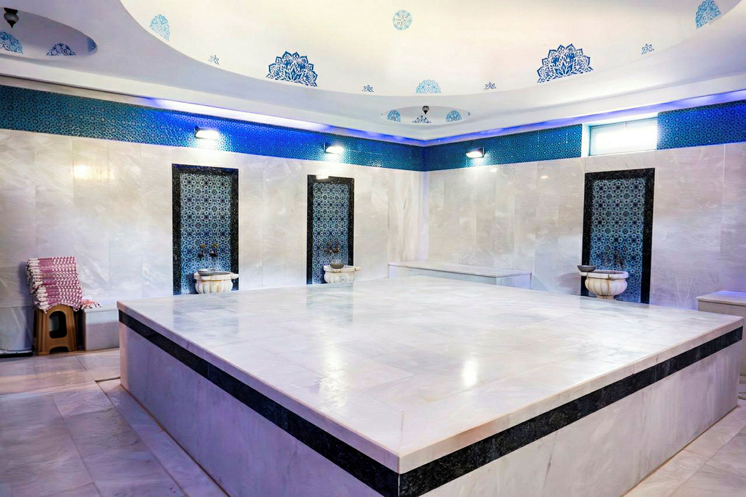 Ett traditionellt turkiskt hamam med marmorväggar, dekorativa detaljer och en stor central plattform. (AI-genererad text)