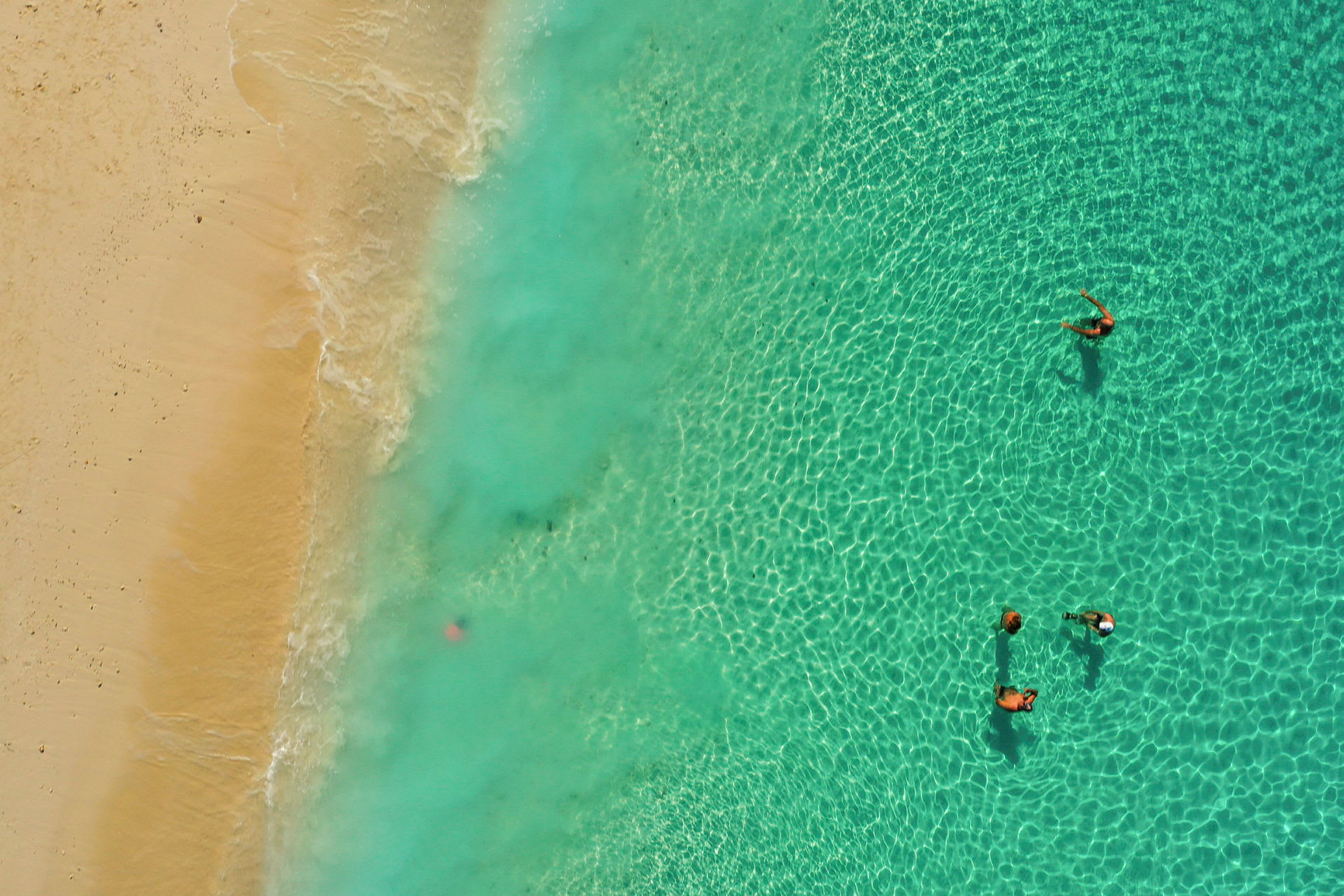 Flygfoto av personer som simmar i havet nära en sandstrand. (AI-genererad text)