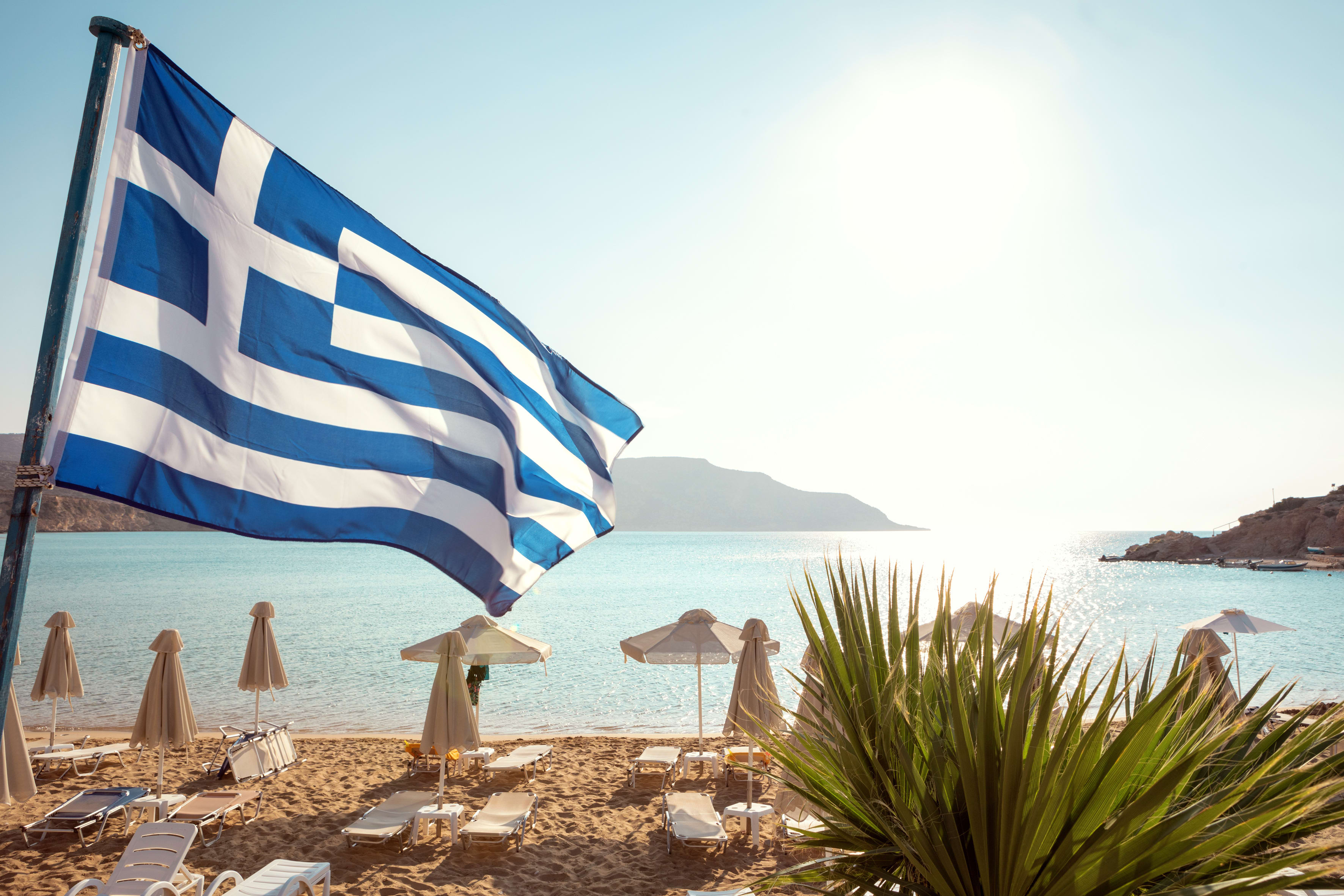 Greklands flagga med strand i bakgrunden
